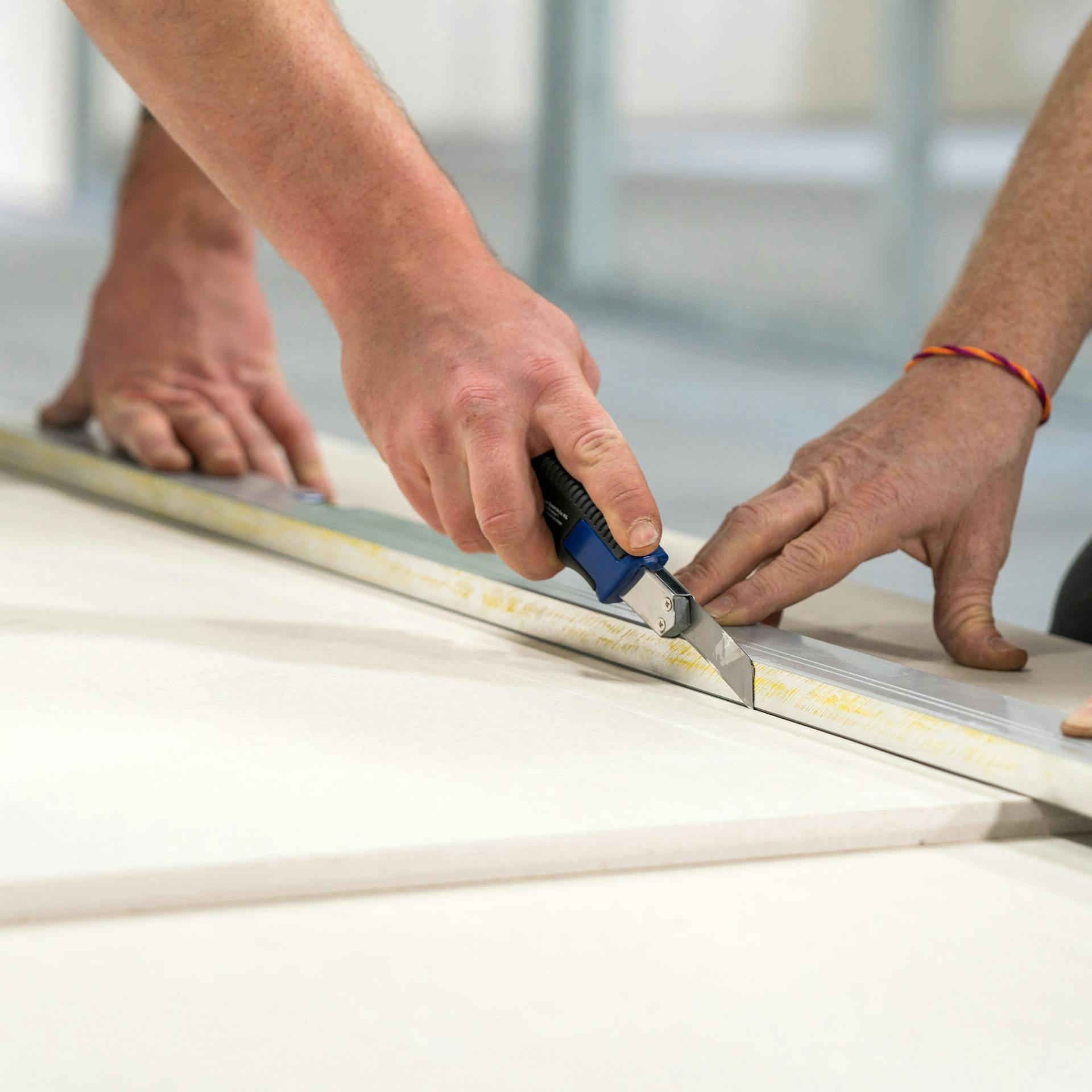 Heimwerker schneiden Trockenbauplatten mit dem Cuttermesser zu.
