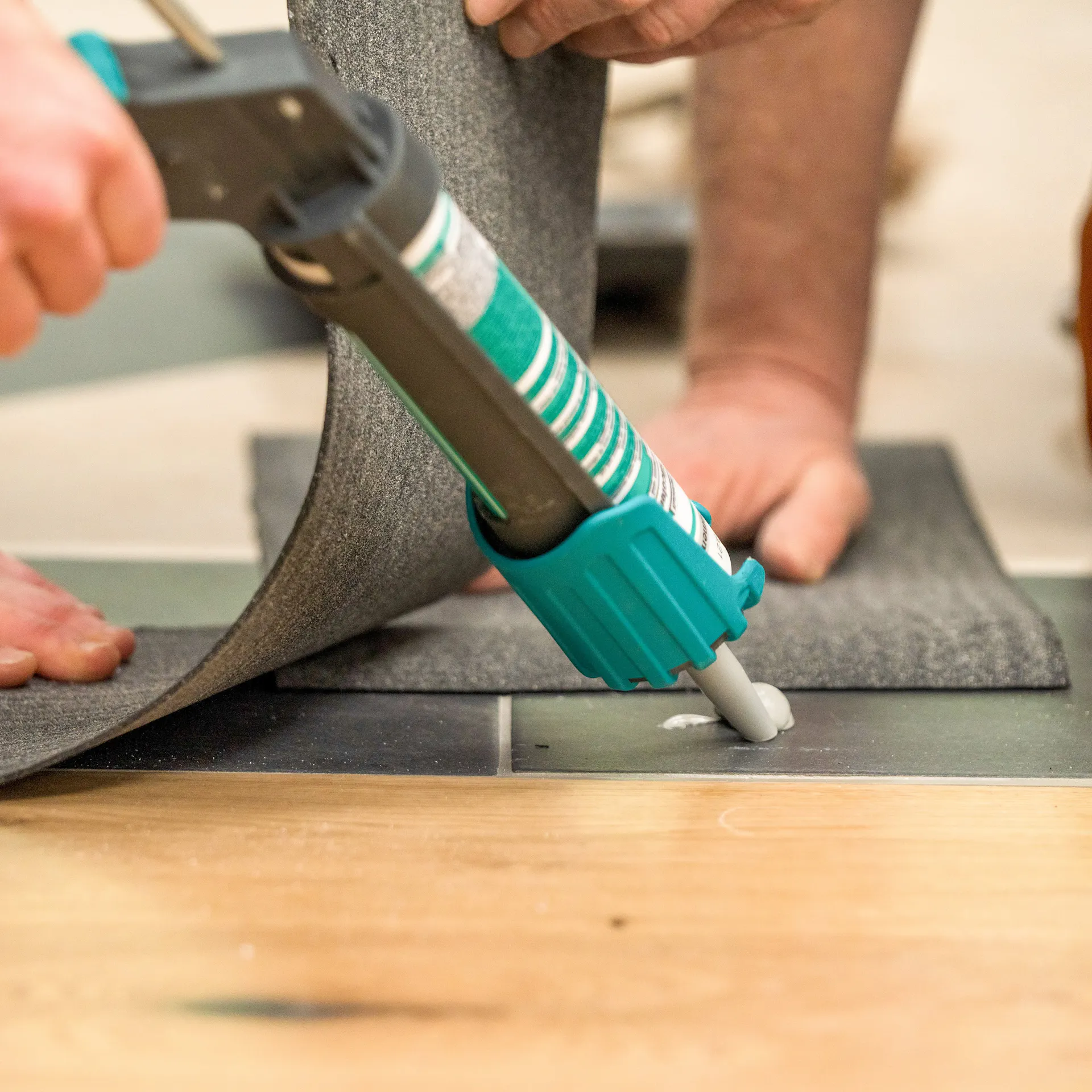 Handwerker bringt Dachpappe mit Silikon unter die Steine an.