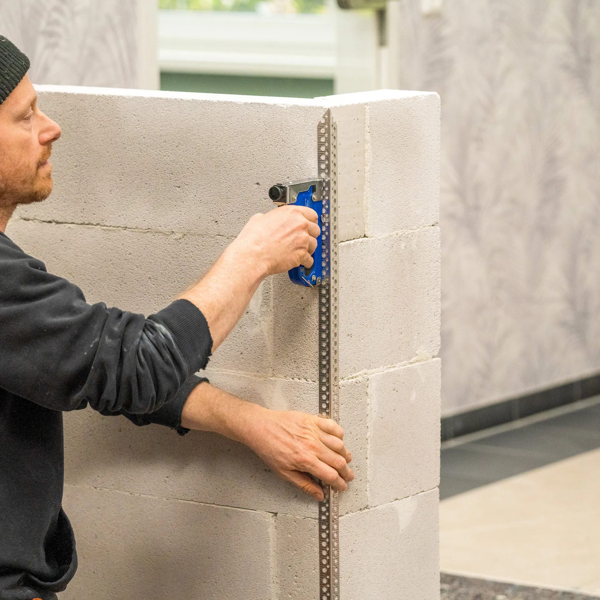 Handwerker tackert Eckschutzschienen an die Wand.