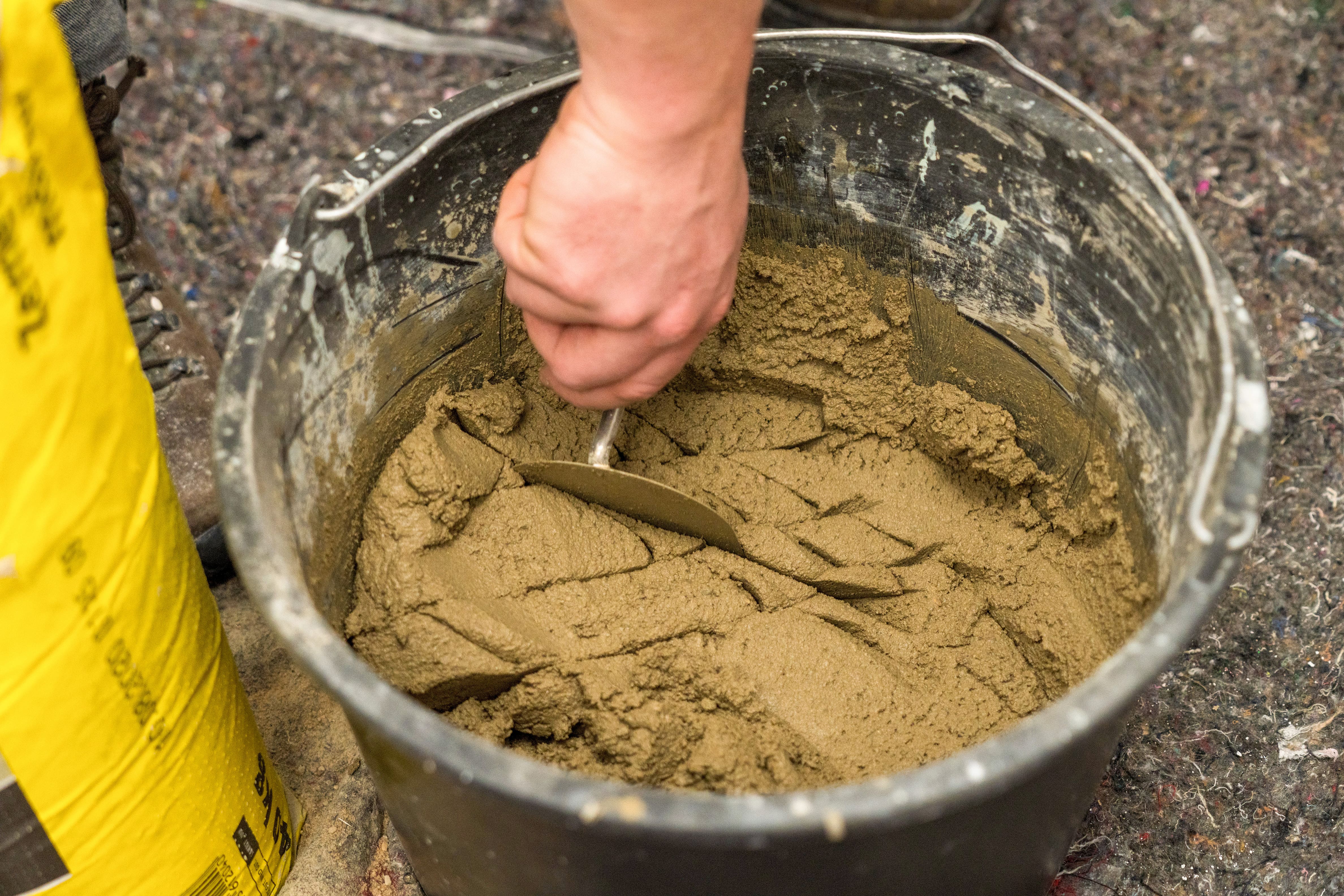 Handwerker nimmt Mörtel aus dem Eimer mit einer Kelle heraus.