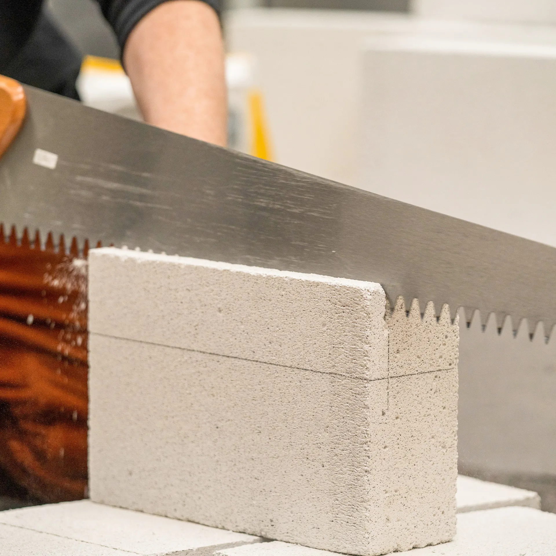 Handwerker schneidet Porenbetonstein mit einer Handsäge zu.