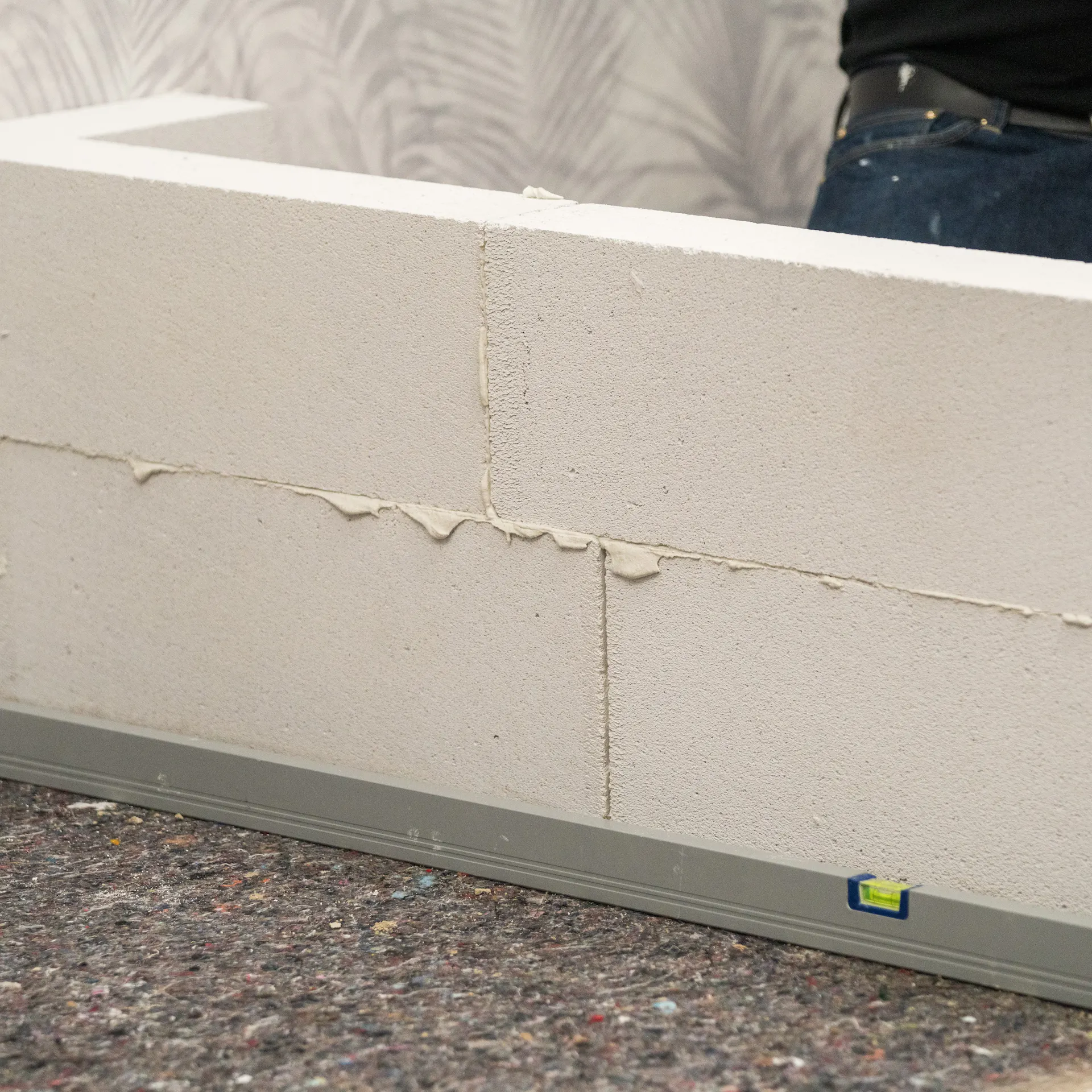 Handwerker setzt die zweite Reihe Porenbetonsteine auf die Erste.