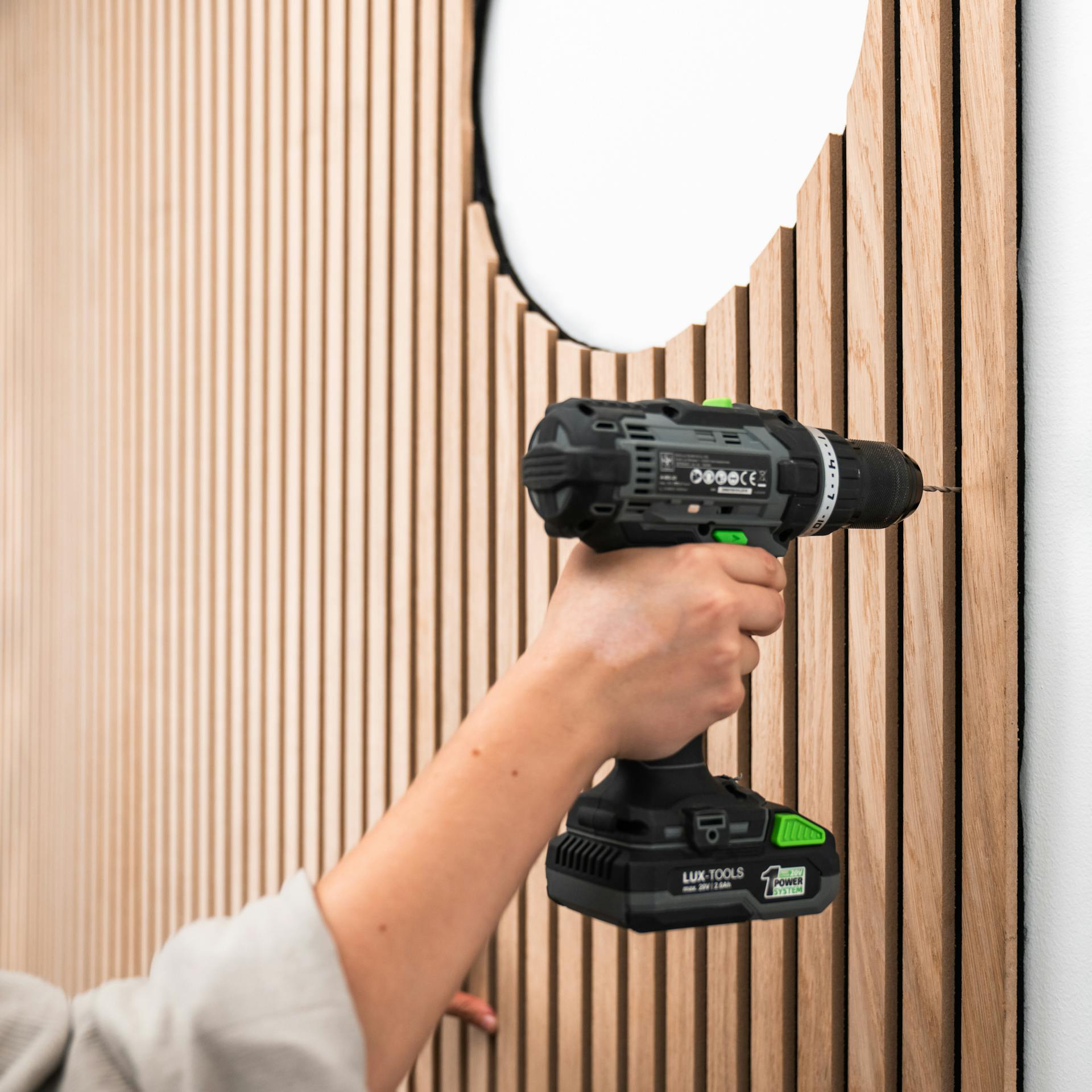 Person bohrt in das Filz der Akustikpaneele.