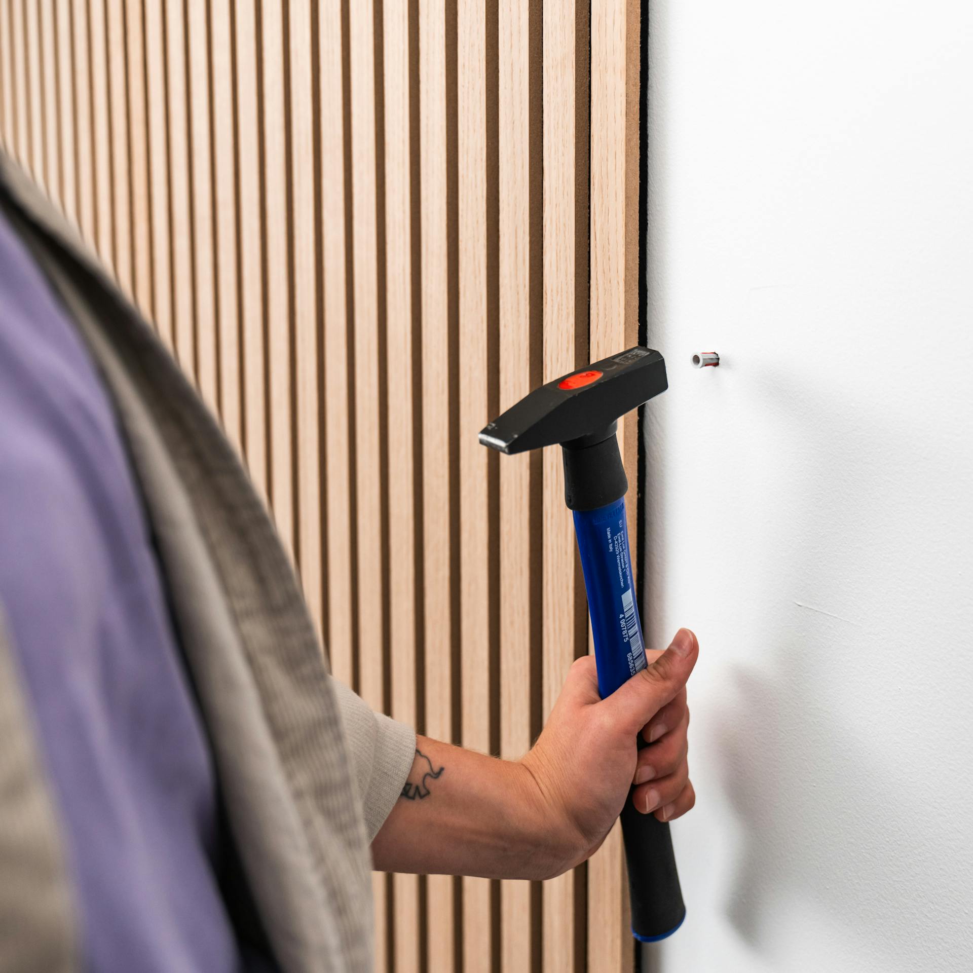 Die Handwerkerin hämmert einen Dübel in die Wand.