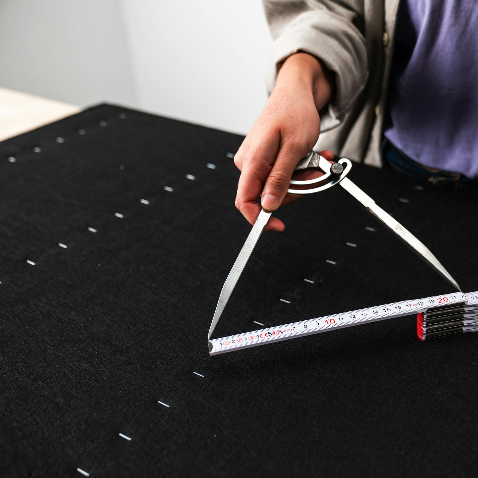 Handwerkerin misst die Kreisgröße mit einem Maßband aus.