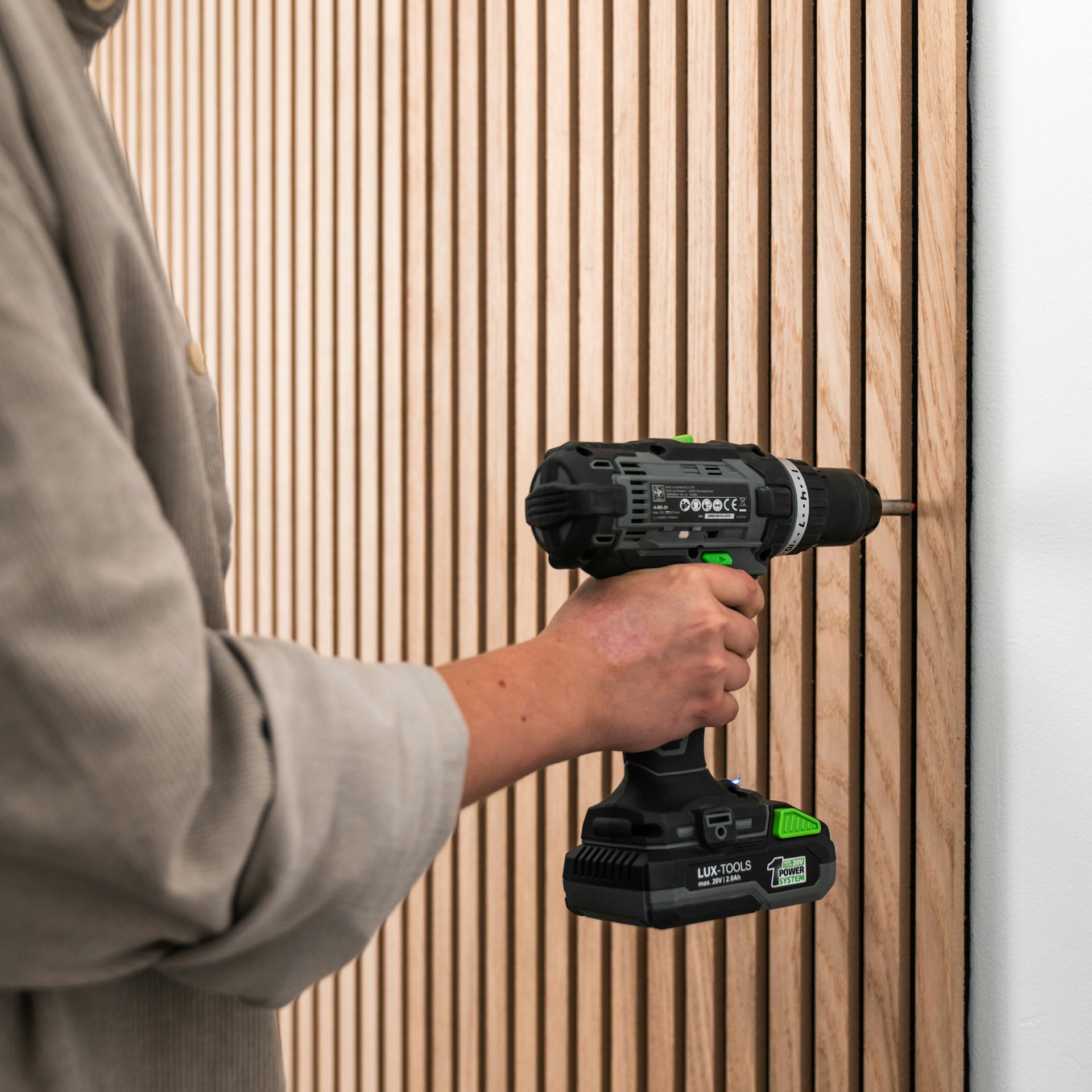 Person verschraubt ein Akustikpaneel an der Wand.