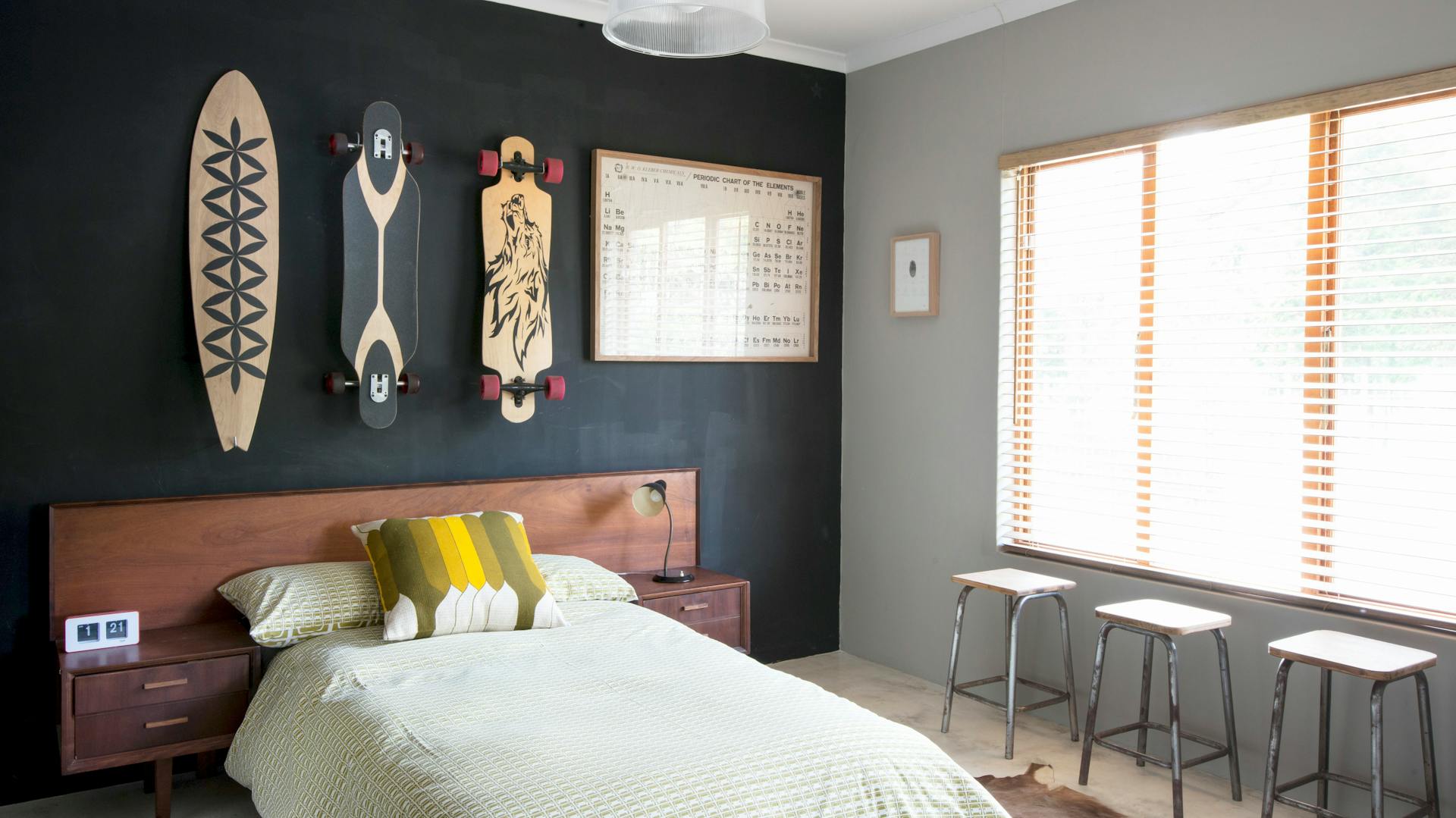 Camera da letto con tre longboard sopra il letto. Alla finestra, tre sgabelli.