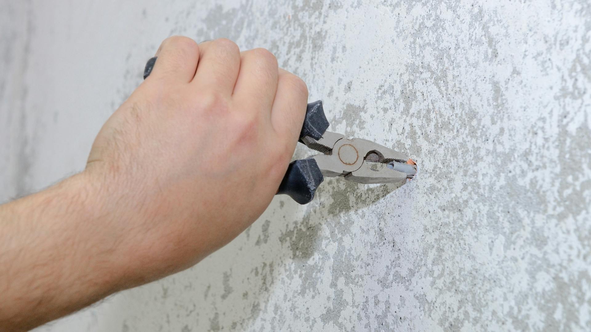 Dübel wird mit einer Zange aus der Wand gezogen