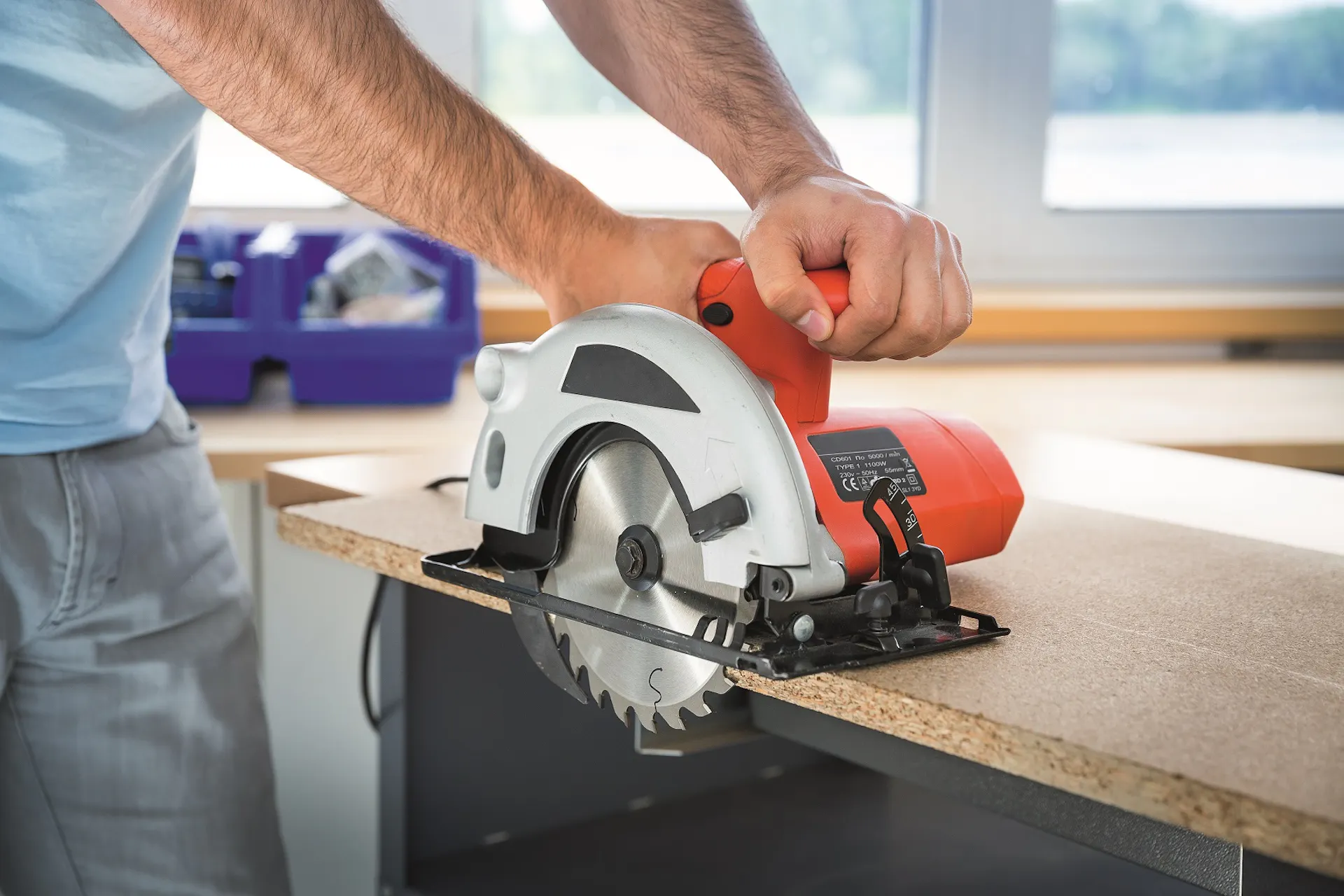 Un bricoleur utilise une scie circulaire pour découper un panneau.