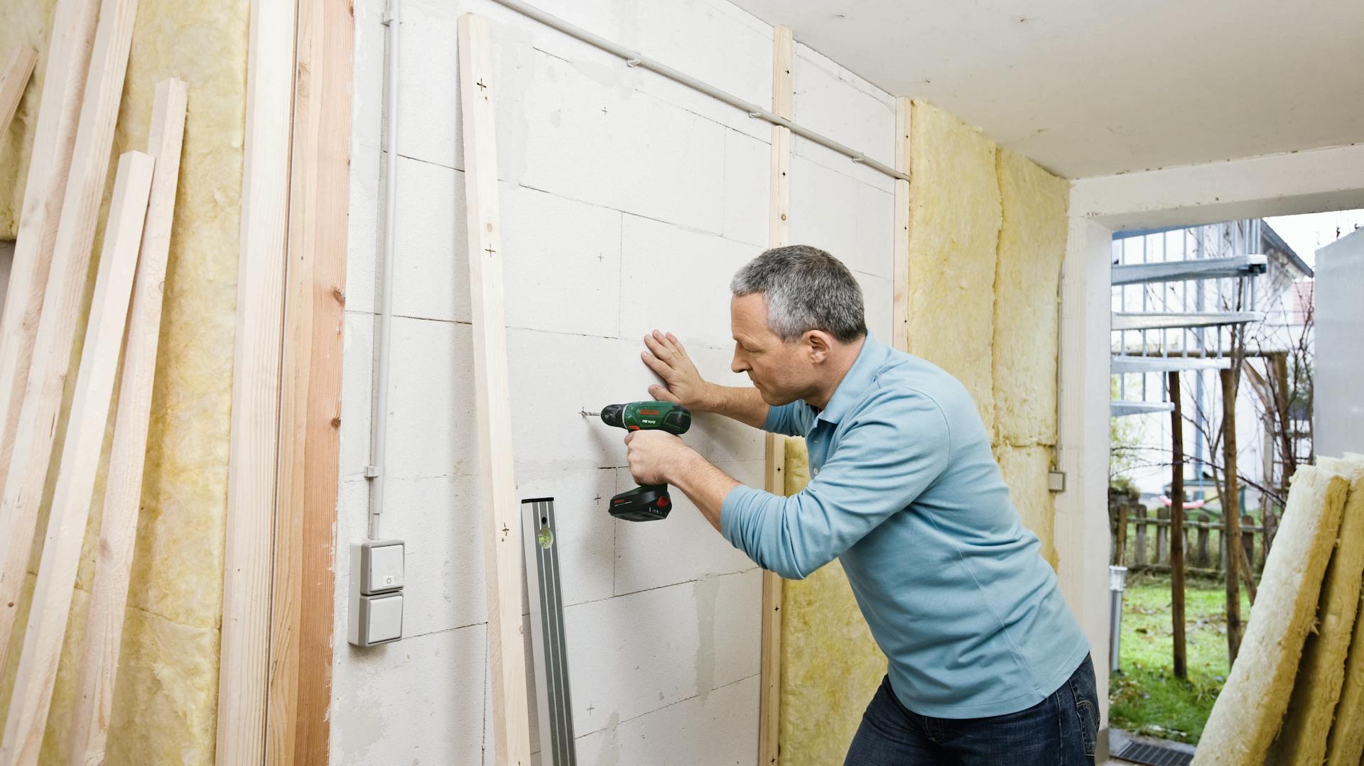 Untergrund wird mit einem Dübel und Bohrer sowie Schrauben bearbeitet.