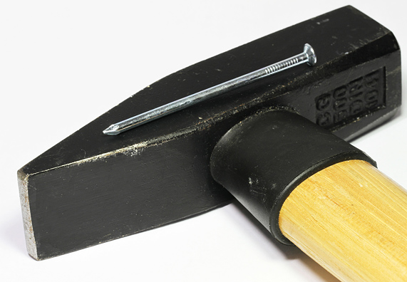 Ein Stahlstift liegt auf einem Hammer. 