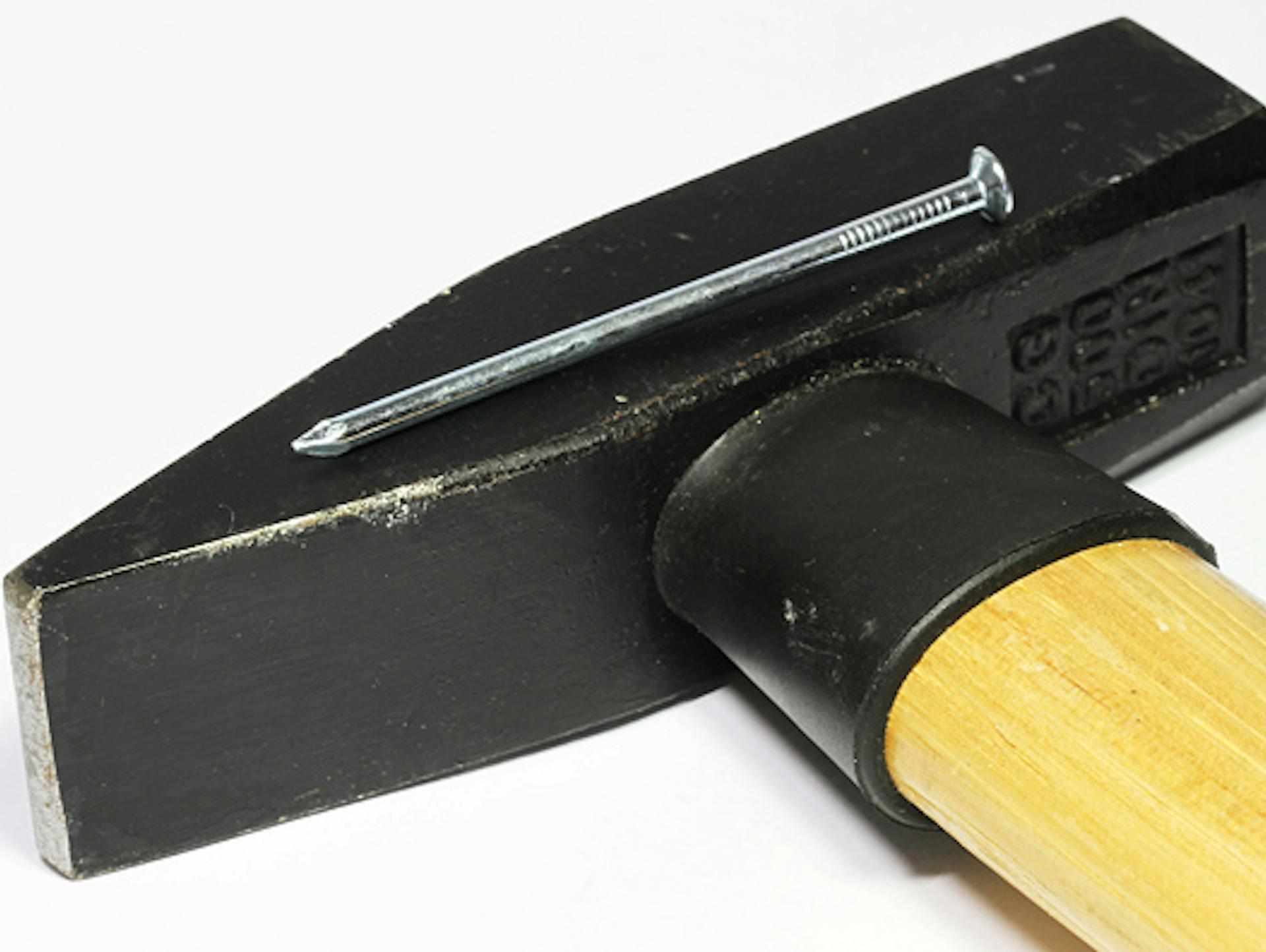 Ein Stahlstift liegt auf einem Hammer.
