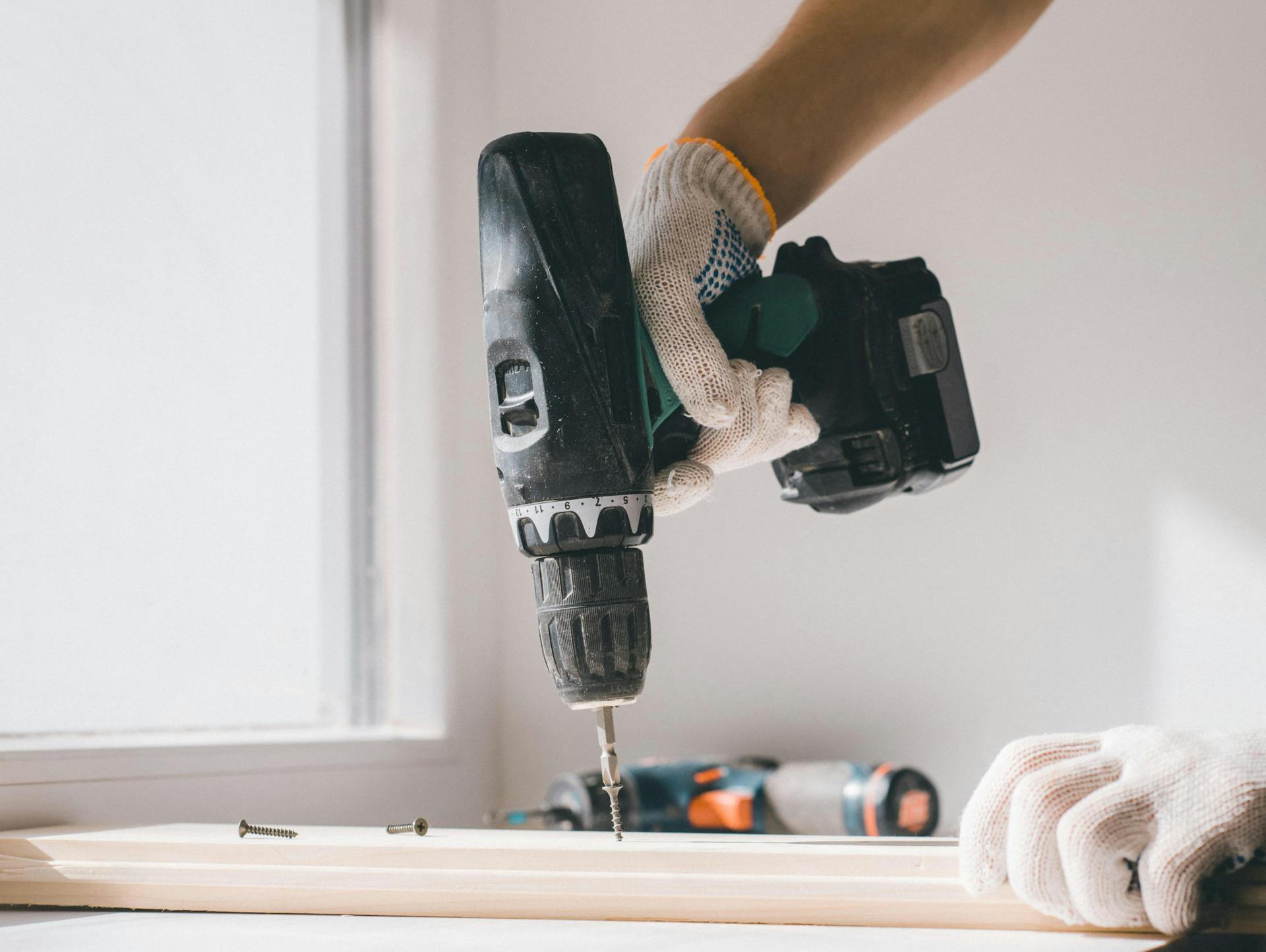 Egy ember egy lyukat fúr egy akkus fúrógéppel.