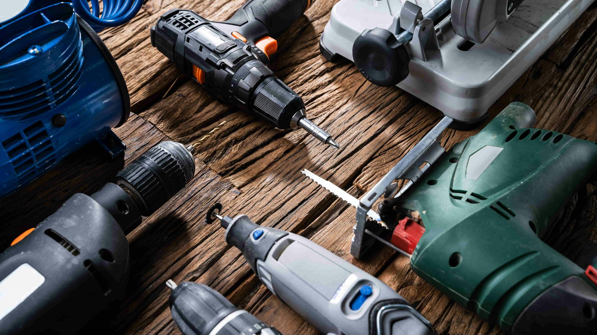 Különböző elektromos kéziszerszámok egy asztalon.