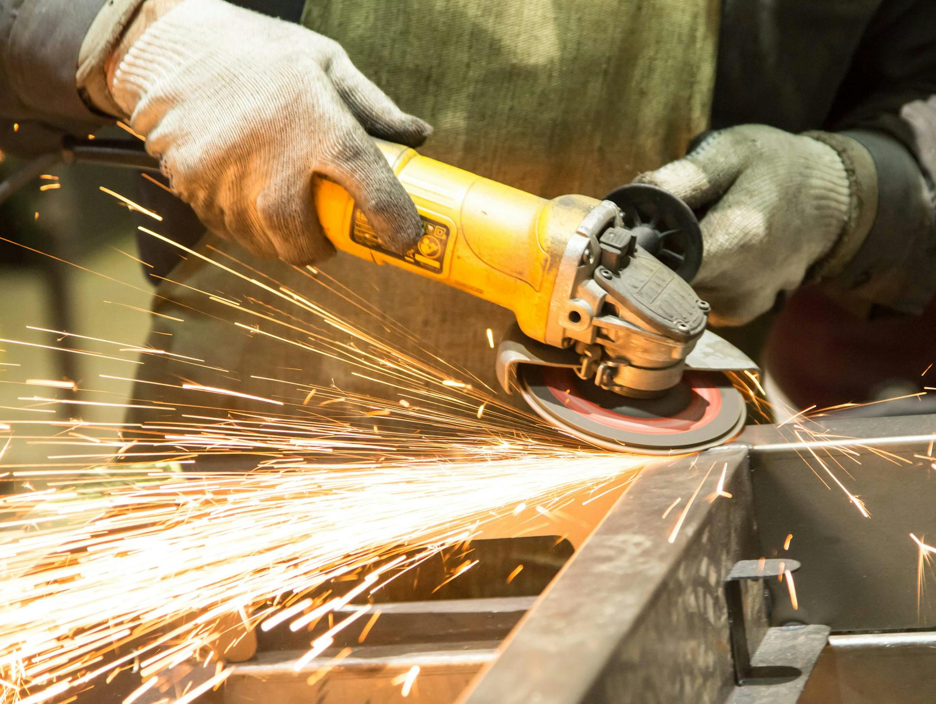 Egy ember sarokcsiszolóval köszörül.