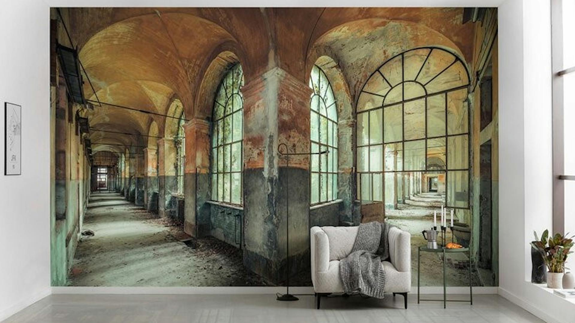 Eine Fototapete mit einem großen, alten Gebäude in einem Wohnzimmer. Davor stehen ein weißes Sofa und ein Tisch.