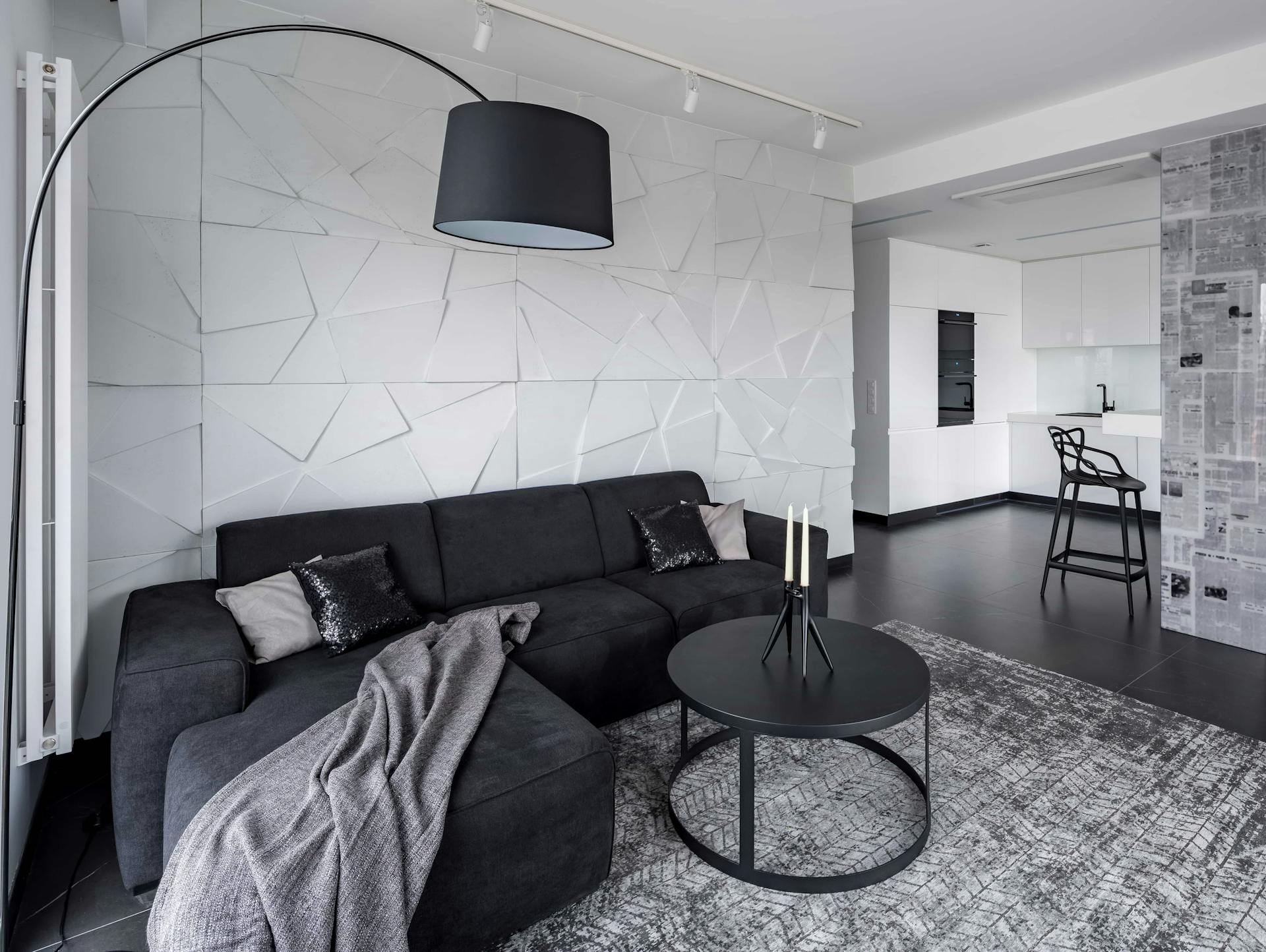 Schwarz-weißes Wohnzimmer mit Deckenspots und Zonenbeleuchtung durch Stehlampe