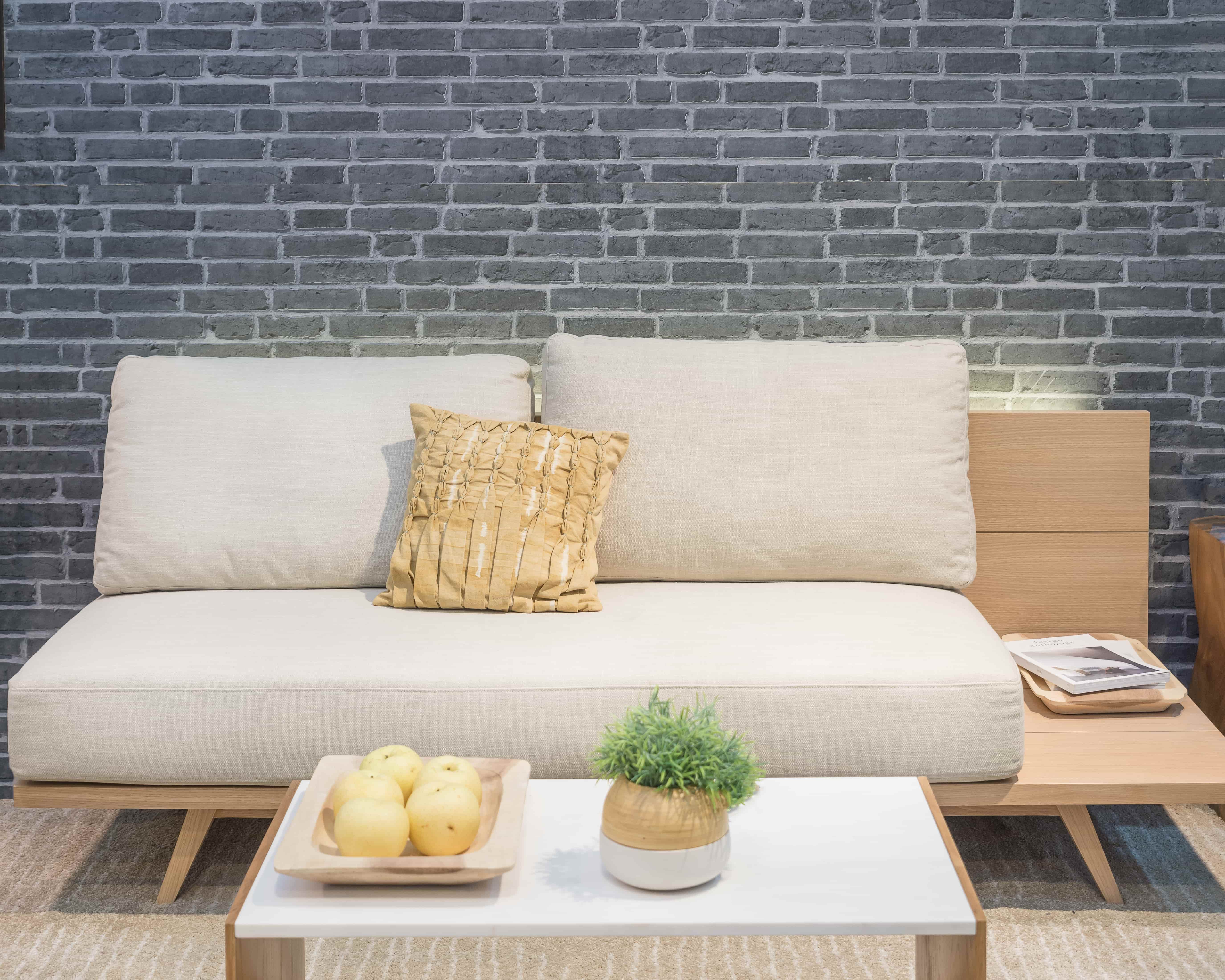 3D tapeta s efektem kamene, před ní světlá pohovka a konferenční stolek.