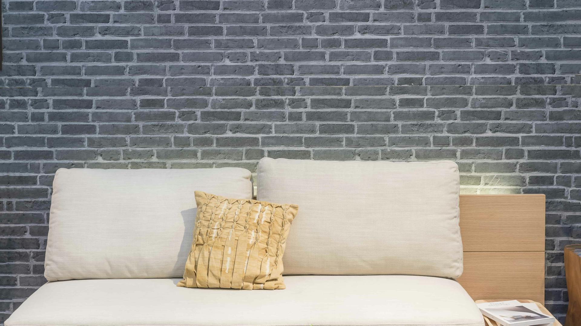 Sofa vor Wand mit blau-grauer Steinoptik-Tapete in 3D-Effekt