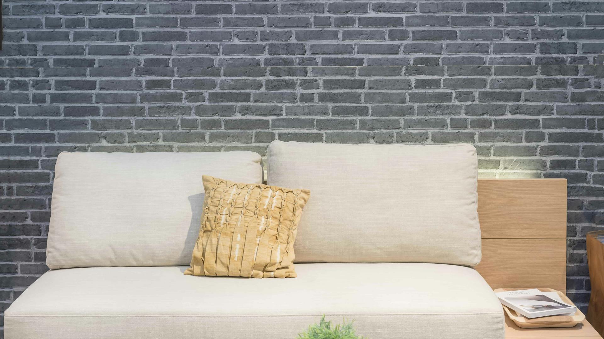 3D-Tapete in Steinoptik, davor ein helles Sofa und Couchtisch.