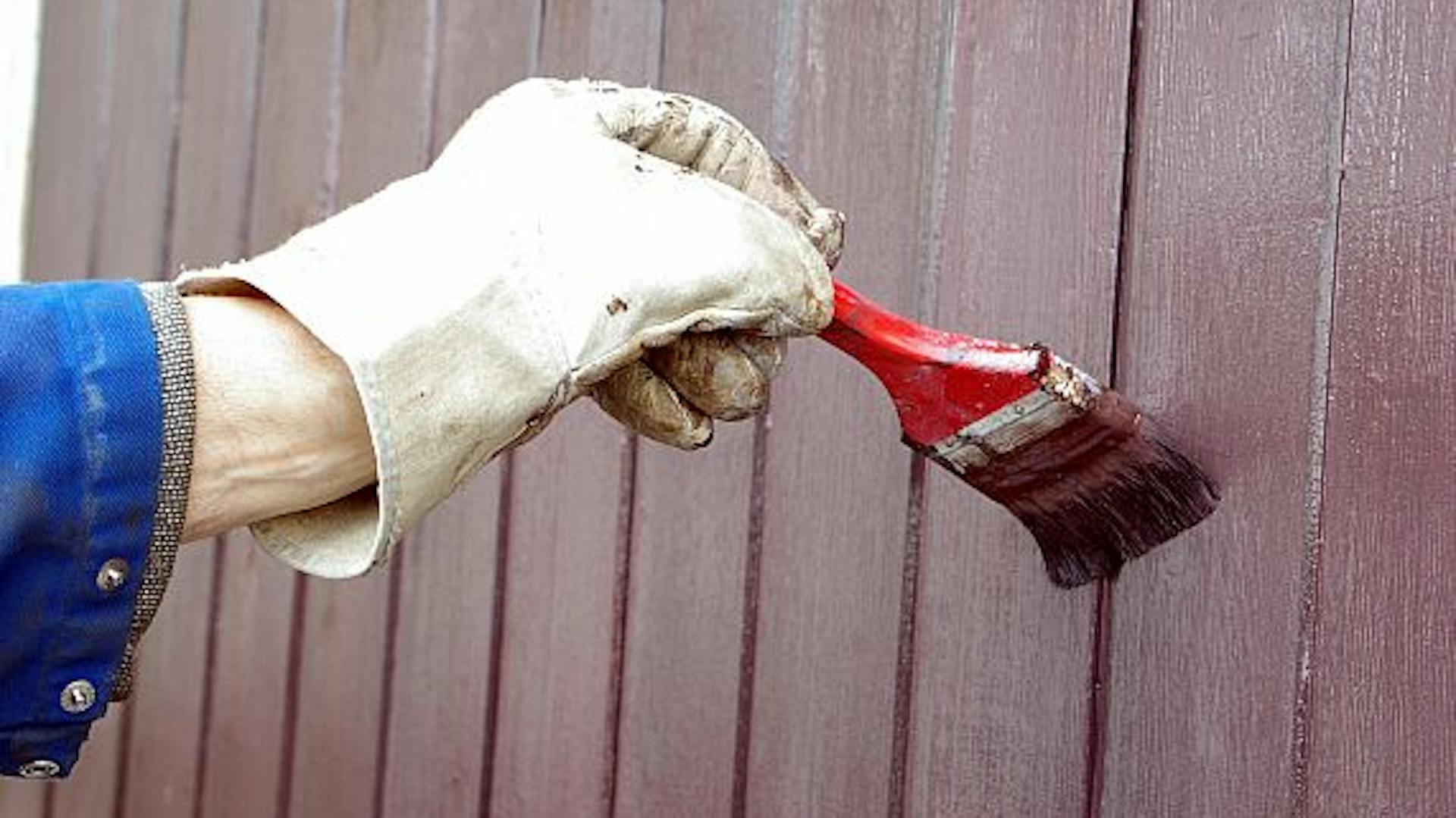 Jemand streicht ein Holz-Garagentor