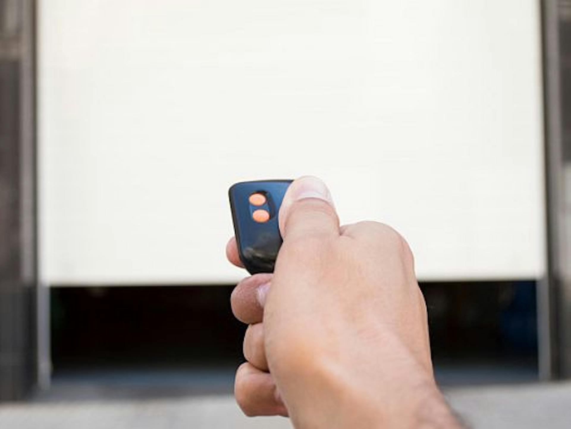 Hand bedient Fernsteuerung für Garagentorantrieb und öffnet Garagentor