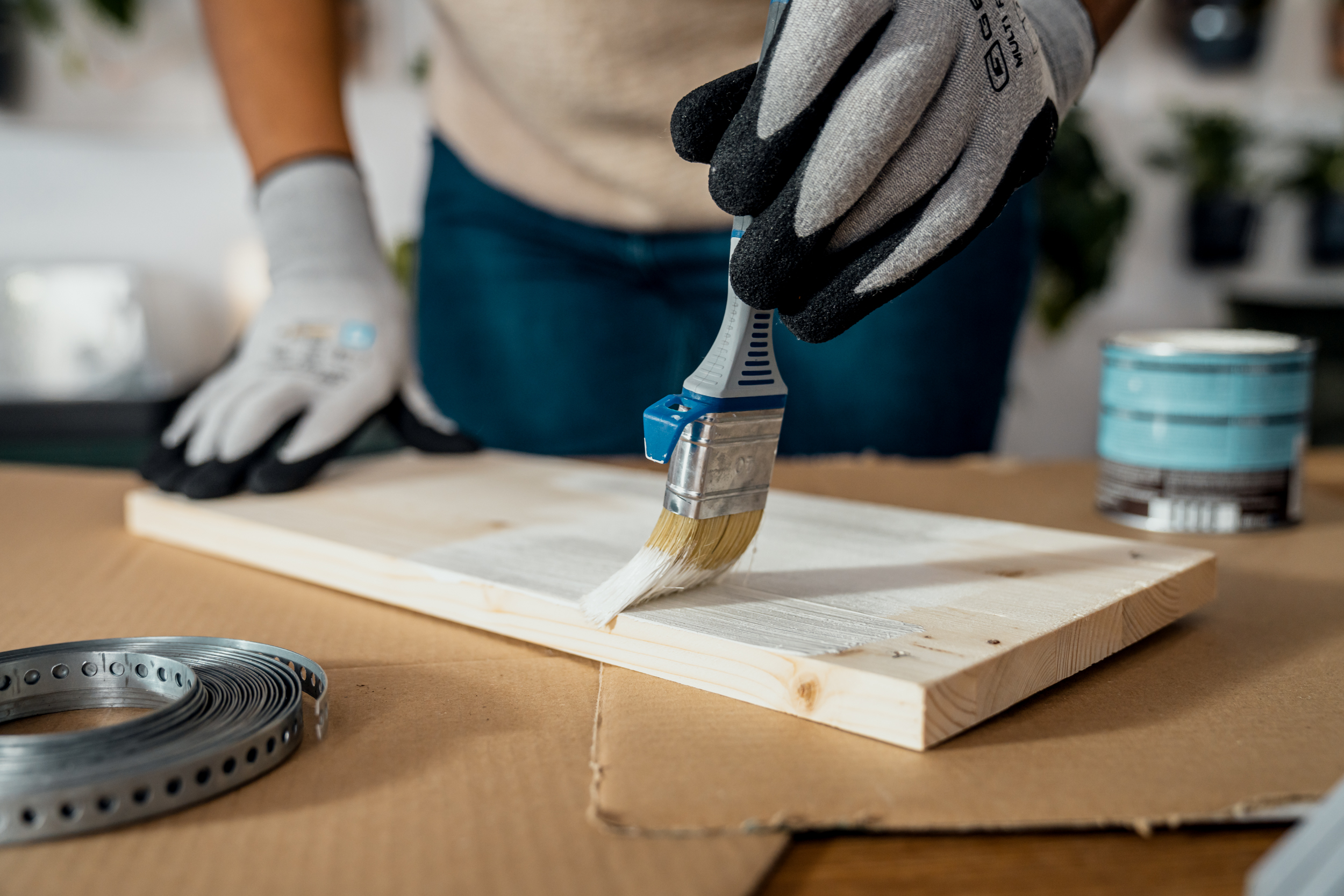 Con un pennello viene applicato uno strato sottile di vernice bianca sul legno naturale.