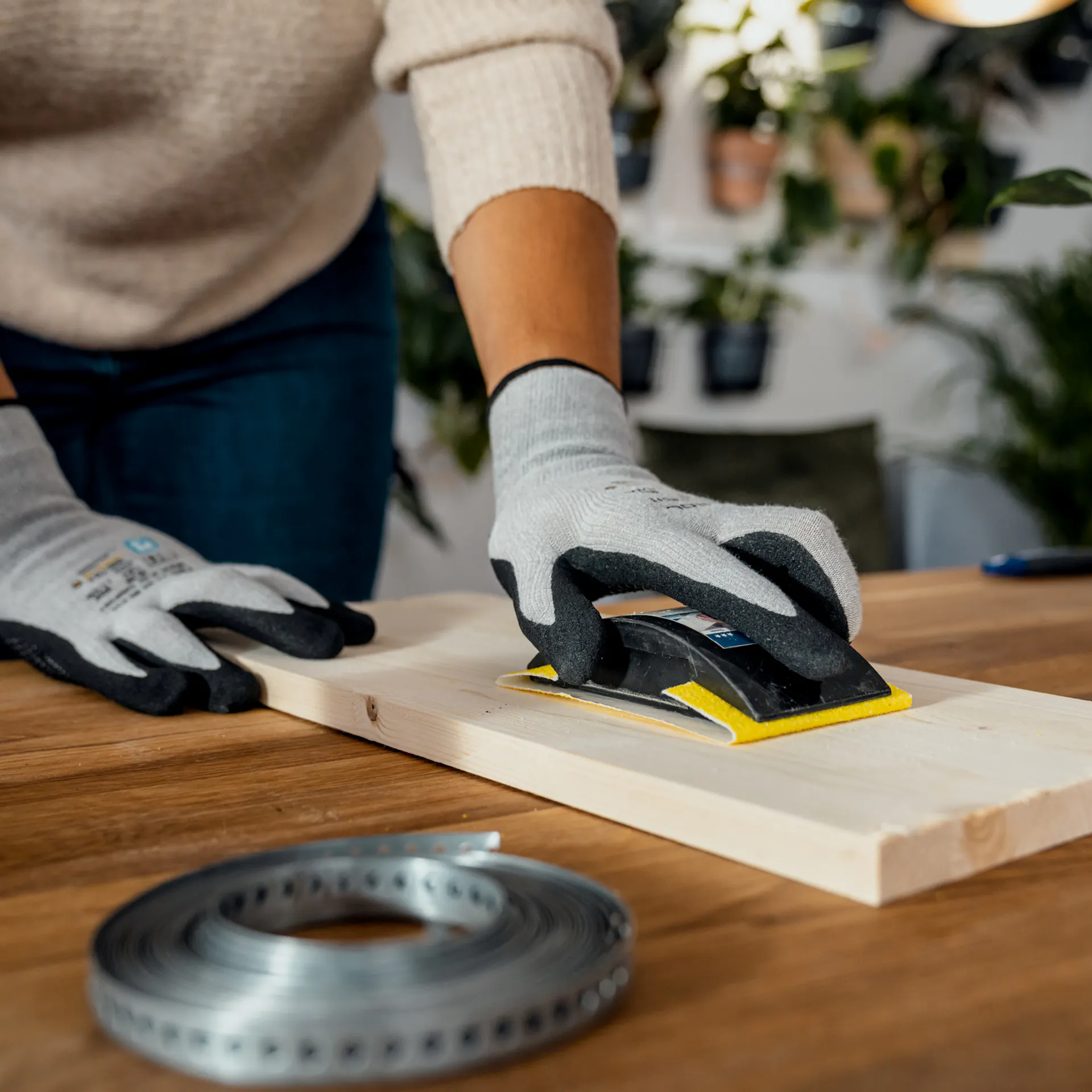 Levigatura di un pannello di legno rettangolare con un blocco abrasivo utilizzando i guanti