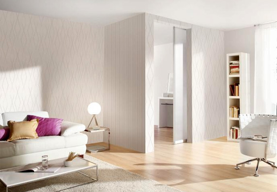 Salotto bianco con divano, poltrona e scaffali illuminato con una luce bianca neutra.