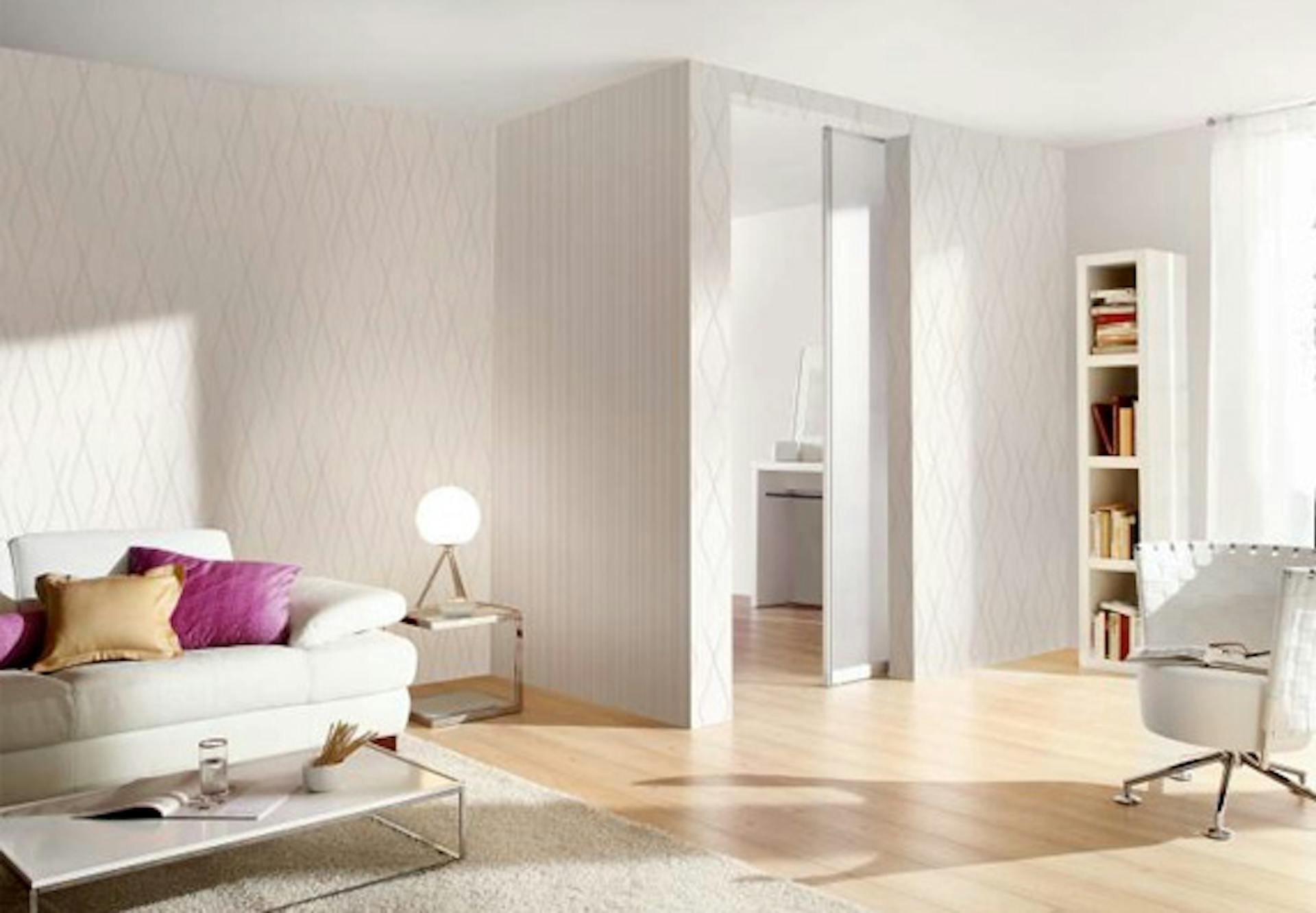 Salotto bianco con divano, poltrona e scaffali illuminato con una luce bianca neutra.