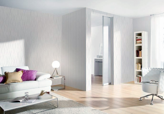 Salotto bianco con divano, poltrona e scaffali illuminato con una luce bianca naturale.