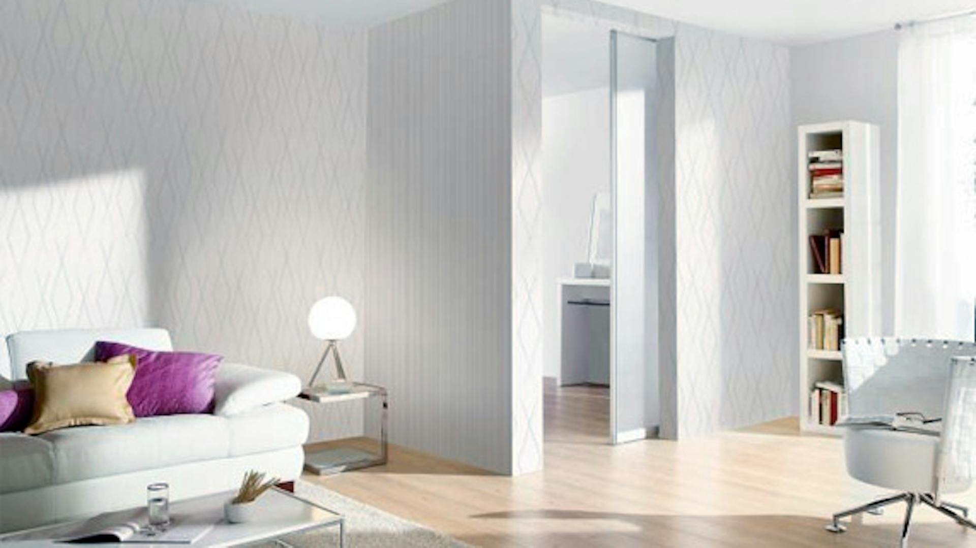 Weißes Wohnzimmer mit Sofa, Sessel und Regal wird mit tageslichtweißem Licht beleuchtet.