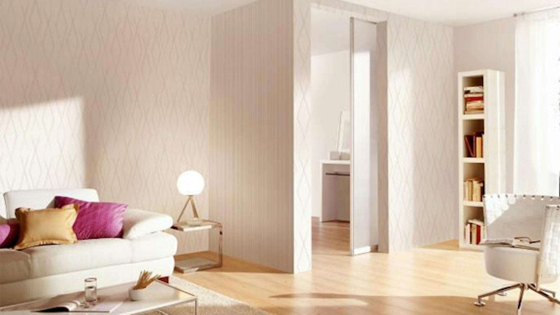 Weißes Wohnzimmer mit Sofa, Sessel und Regal wird mir warmweißem Licht beleuchtet.