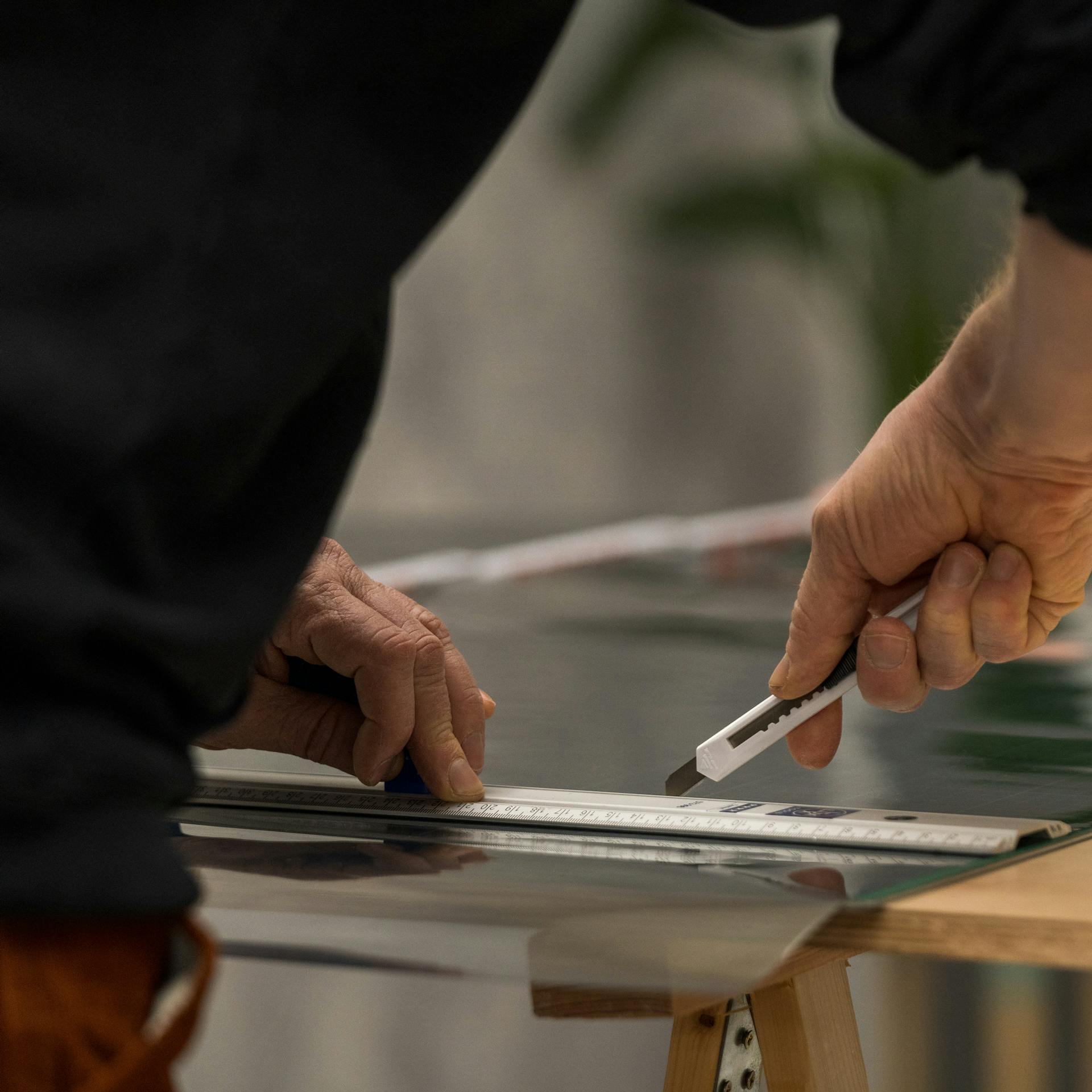 Heimwerker schneidet Klebefolie für das Fenster zu.