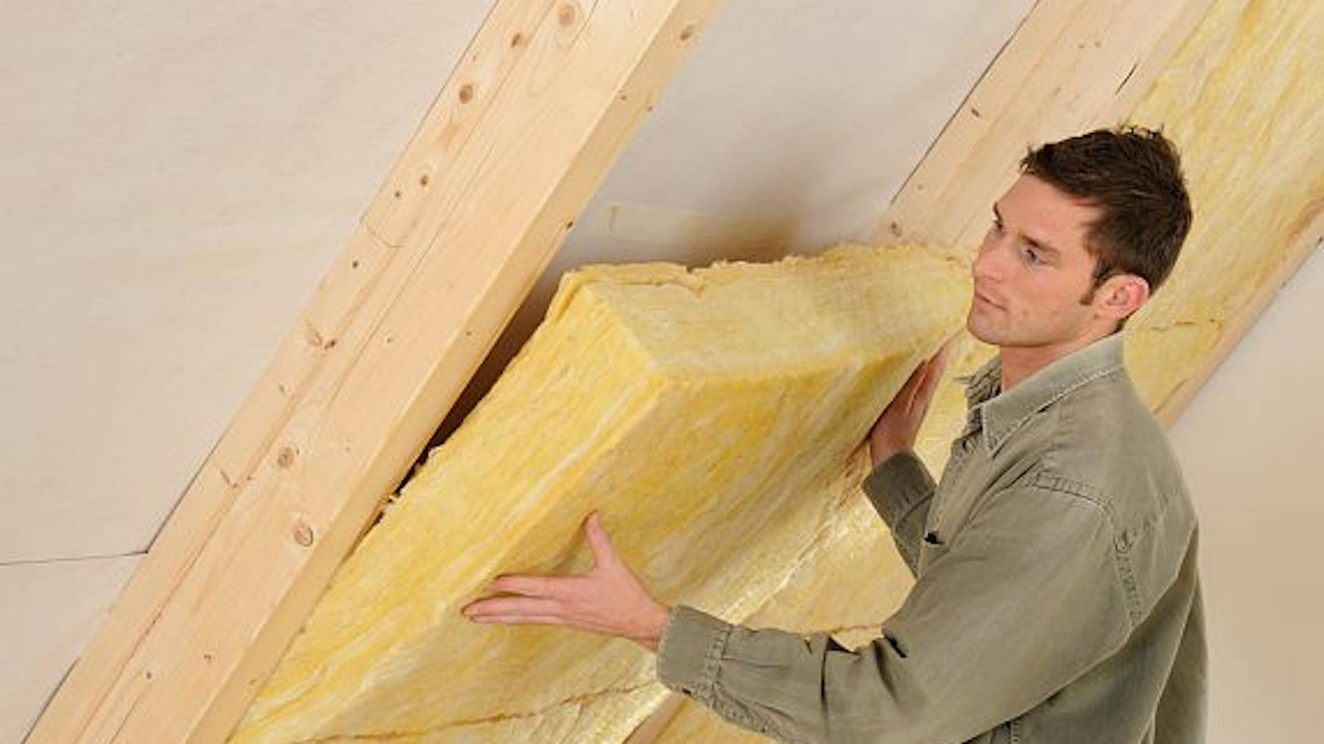 Heimwerker bringt Dämmmaterial am Dach an.