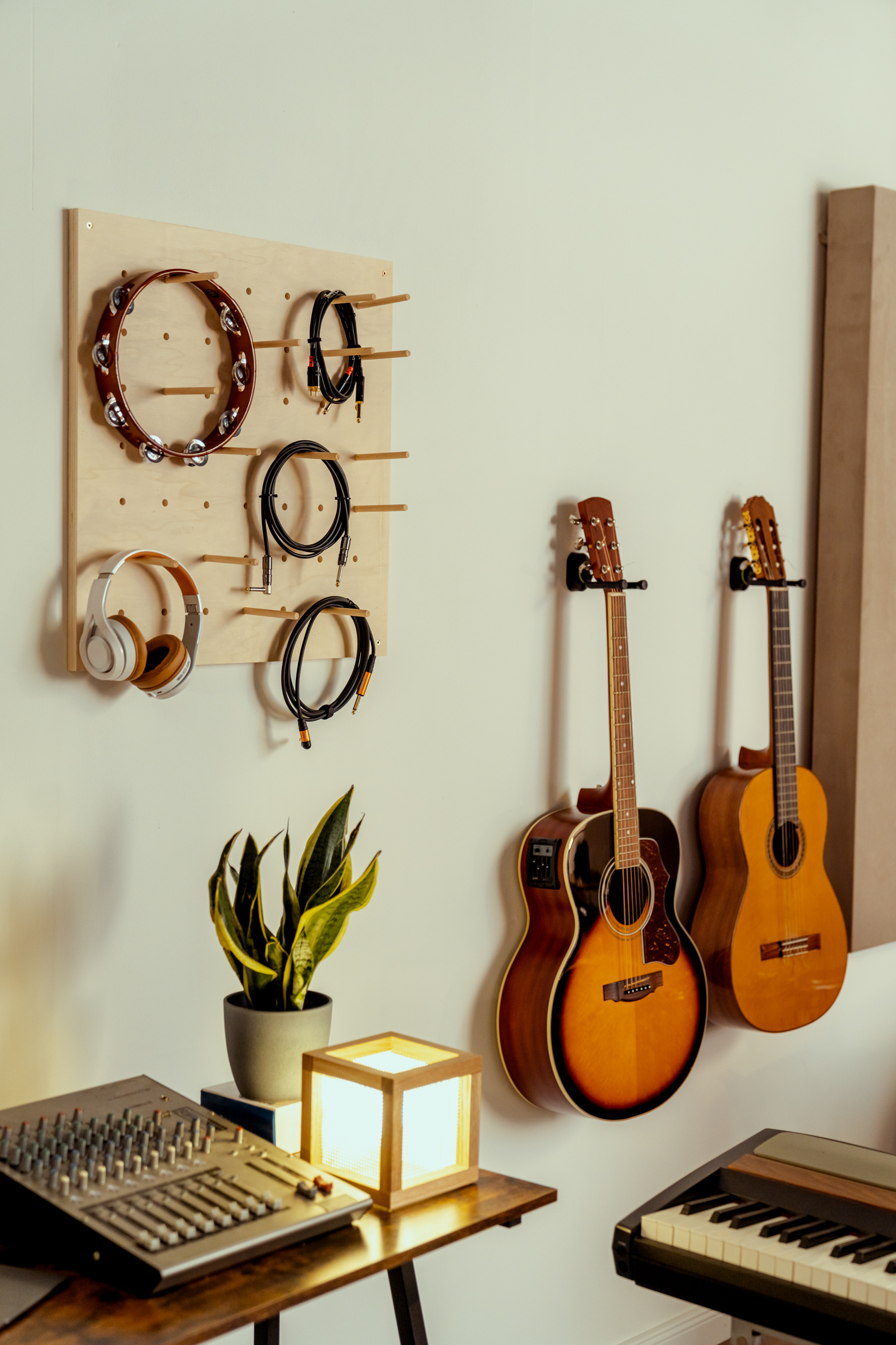 Kabel und Kophörer hängen an einem Pegboard, im Hintergrund hängen Gitarren.