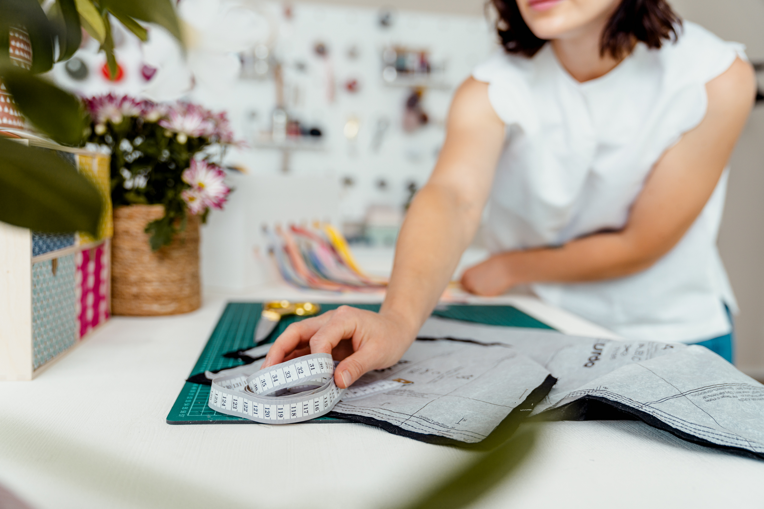Frau misst Stoff auf dem Nähtisch aus.