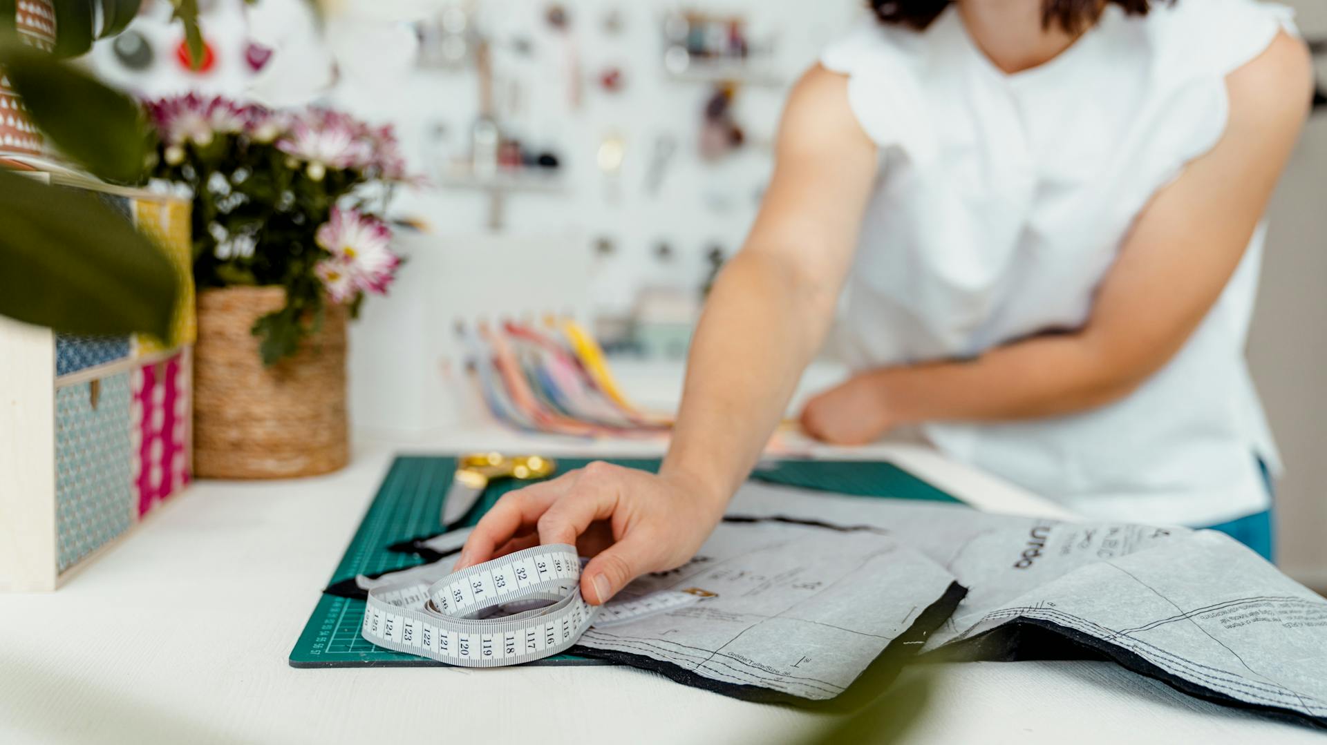 Frau misst Stoff auf dem Nähtisch aus.