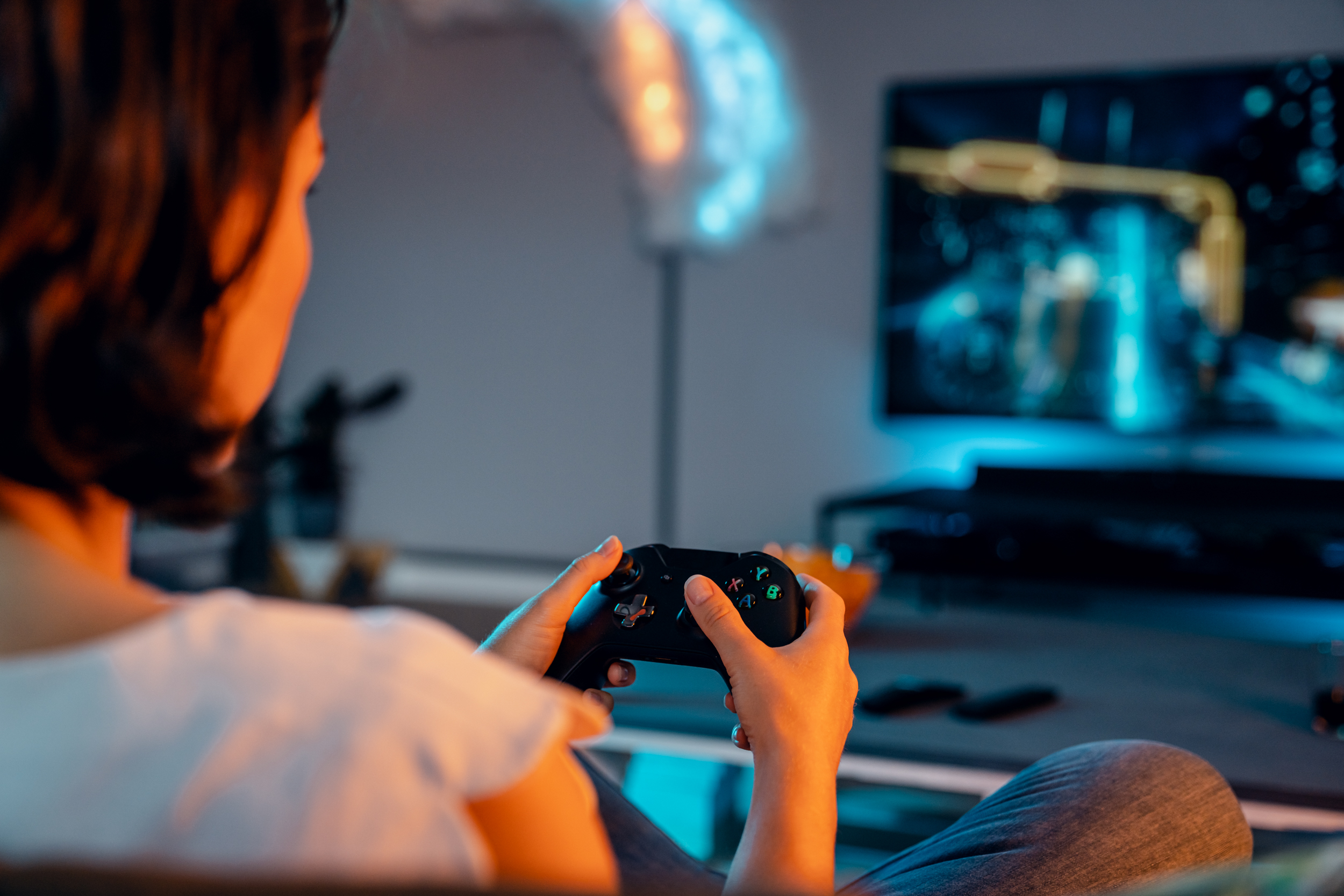 Eine Frau sitzt vor dem Fernseher mit Controller in der Hand.