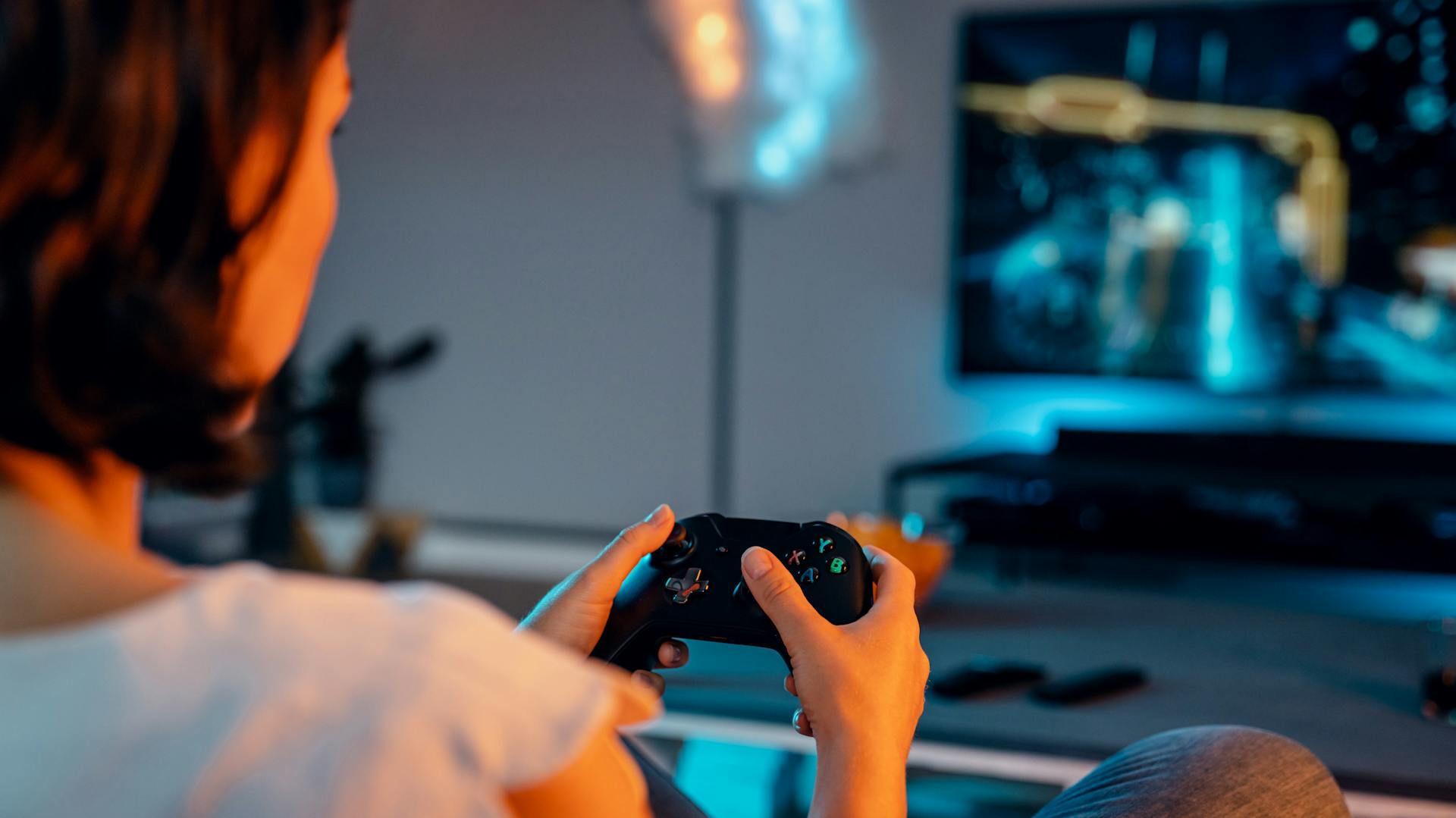 Eine Frau sitzt vor dem Fernseher mit Controller in der Hand.