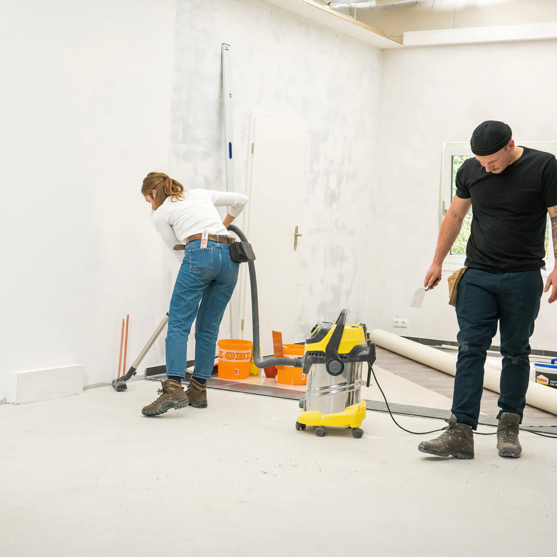Handwerker säubern den Boden um PVC auszulegen.