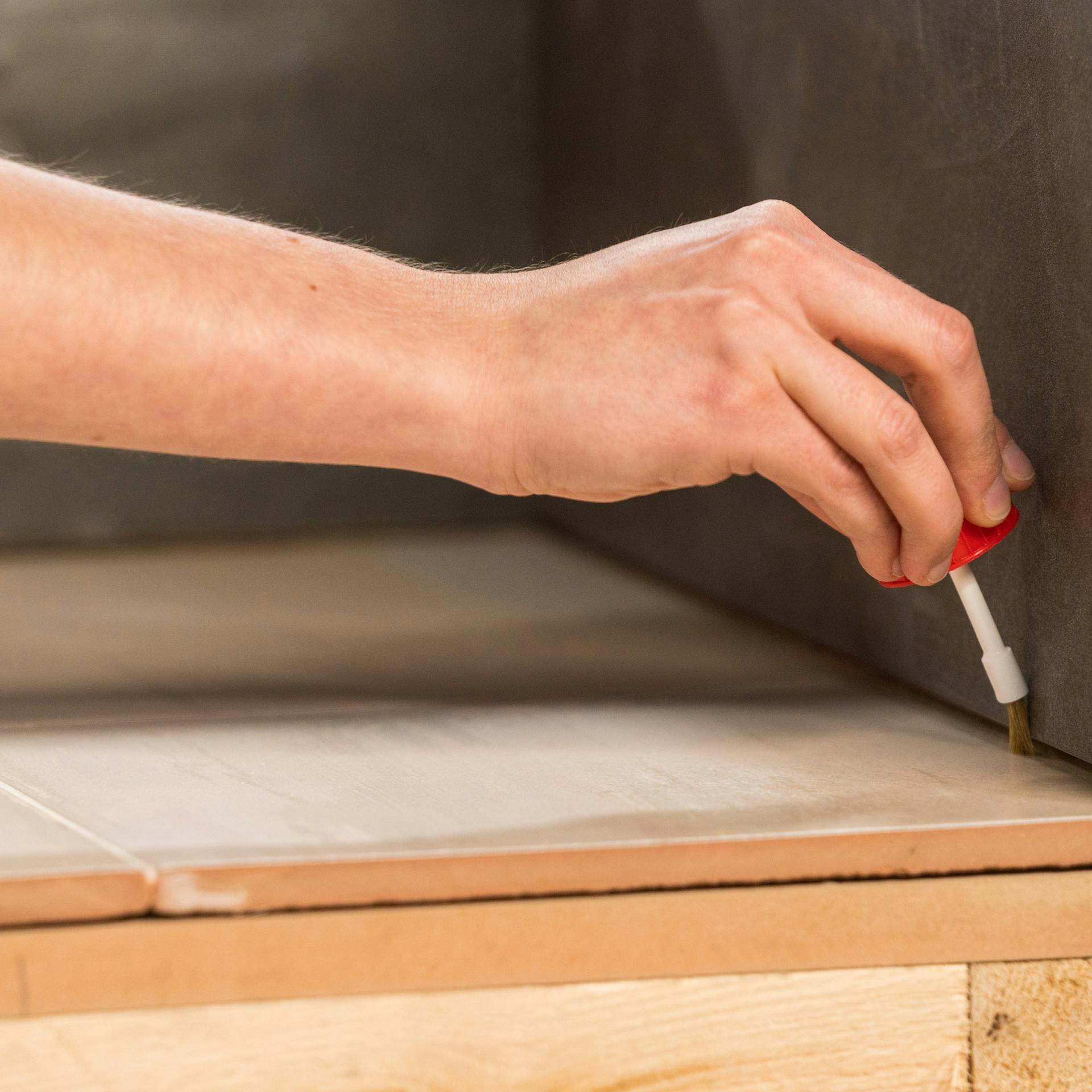 Handwerkerin trägt Primer auf die Fugen auf.