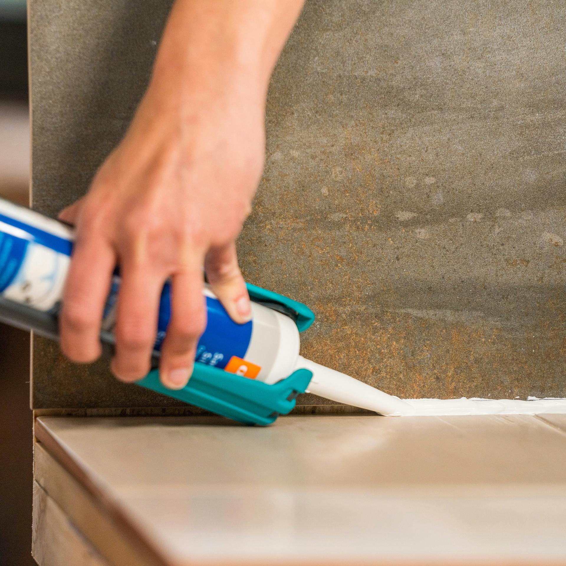 Handwerkerin drück Sillikon mit einer Silikonpistole in die Fuge.