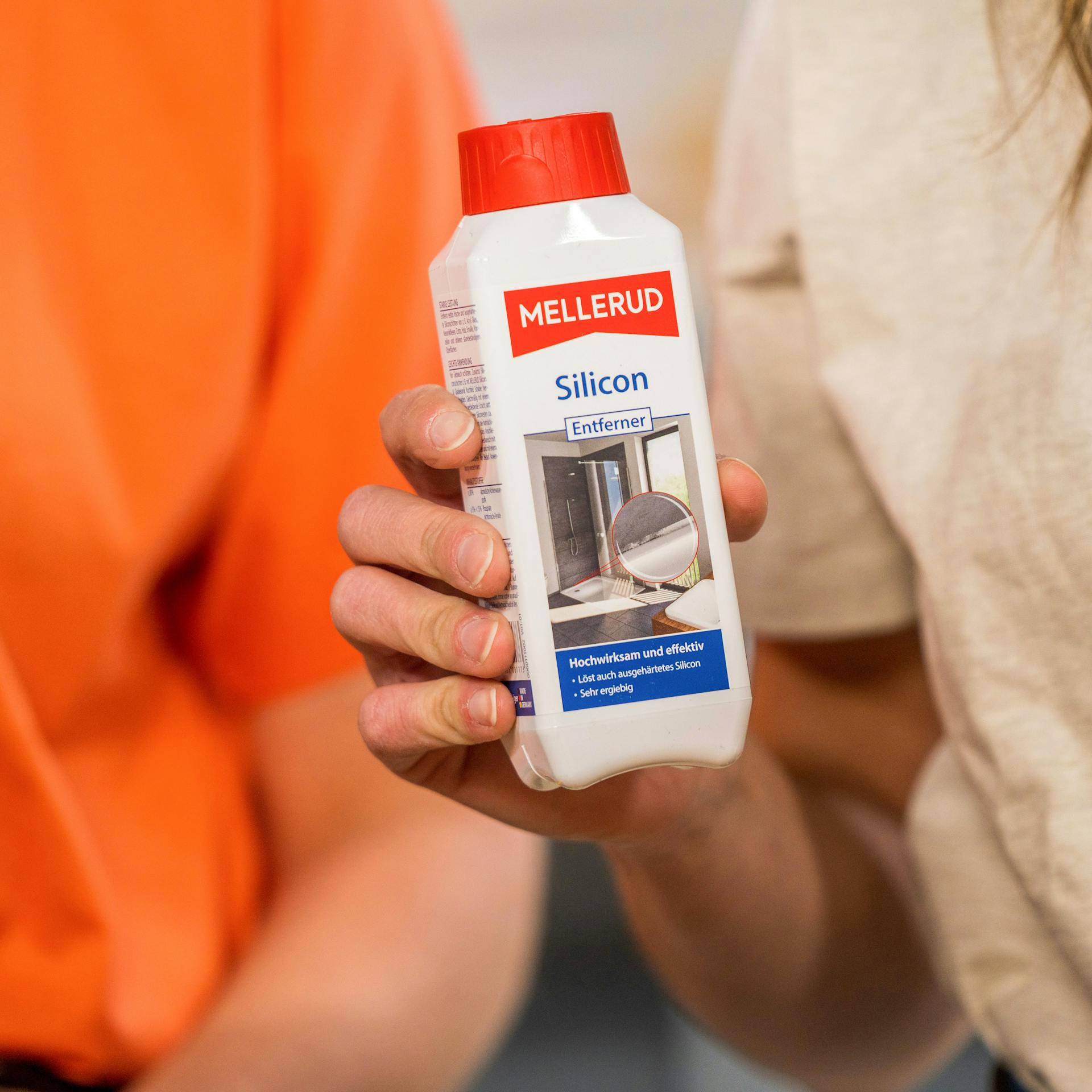 Handwerkerin hält Silikonentferner in der Hand.