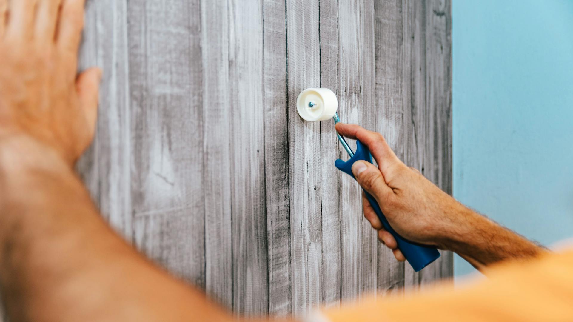 Jemand bearbeitet eine Vinyltapete.