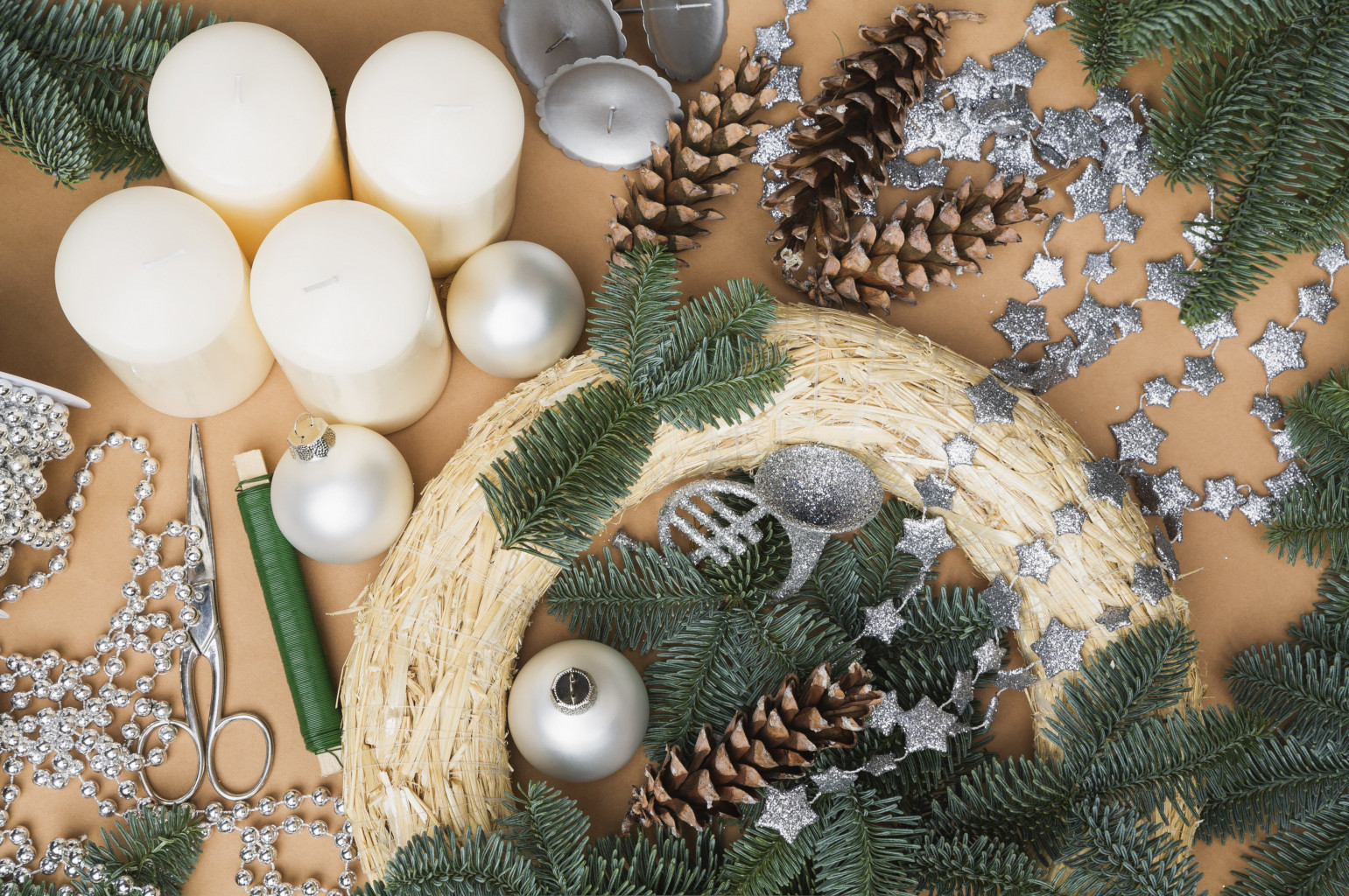 Degli elementi decorativi per la corona dell’Avvento si trovano sul tavolo accanto al pezzo grezzo e a ramoscelli d’abete