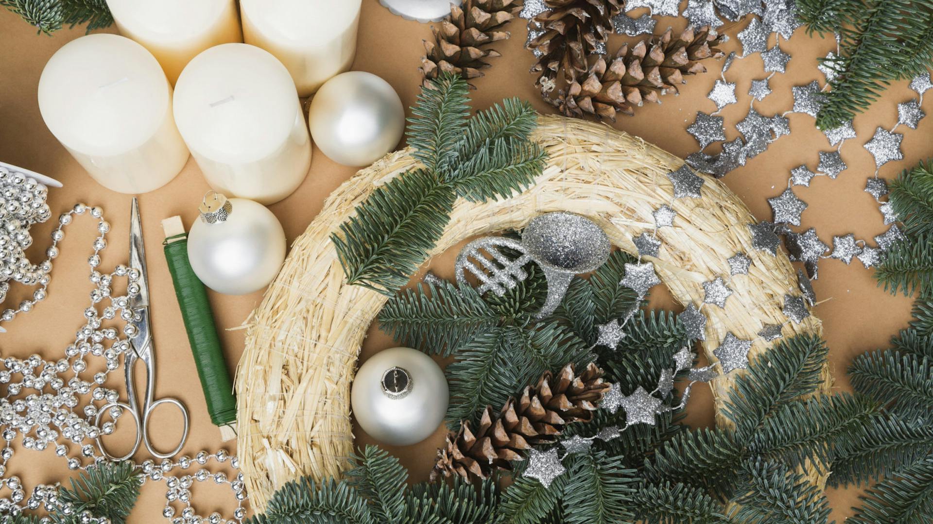 Degli elementi decorativi per la corona dell’Avvento si trovano sul tavolo accanto al pezzo grezzo e a ramoscelli d’abete