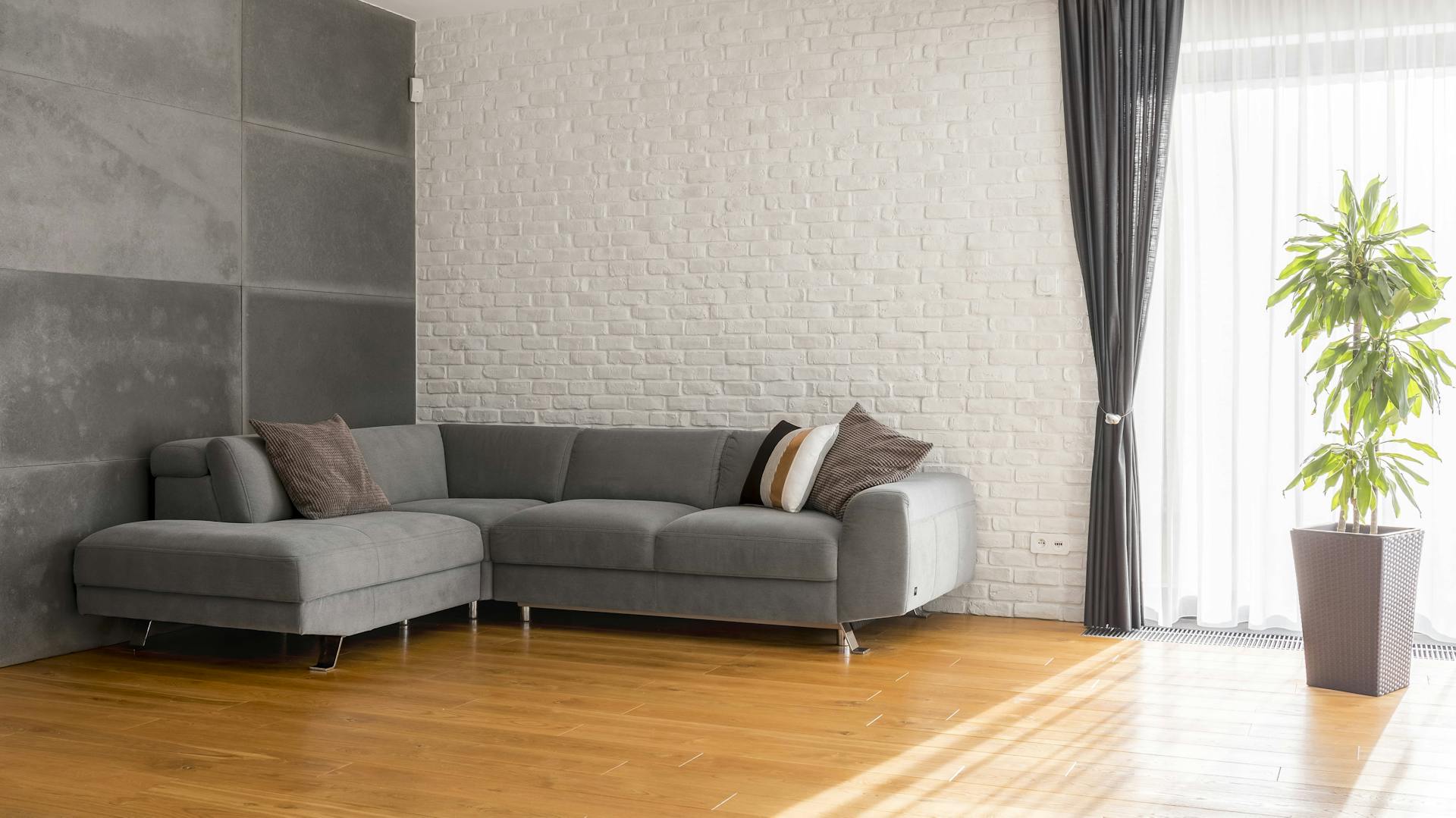 Graues Sofa in Wohnzimmer mit Fliesen als Wandverkleidung