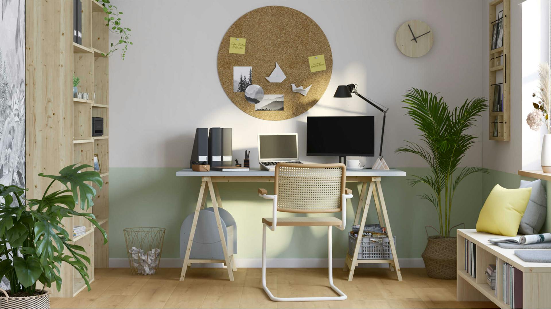 Ein Schreibtisch steht zentriert vor einer Wand, die bis zur Höhe des Tisches grün gestrichen und über jenem eine große runde Korkfläche als Pinnwand angebracht worden ist.
