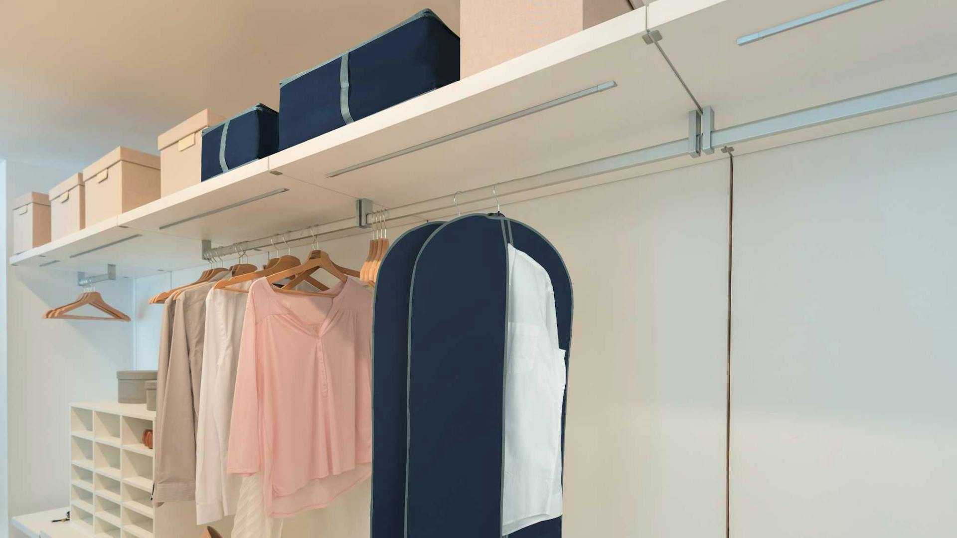 Offener und sortierter Kleiderschrank mit Kleidung auf Bügeln und Organisationsboxen